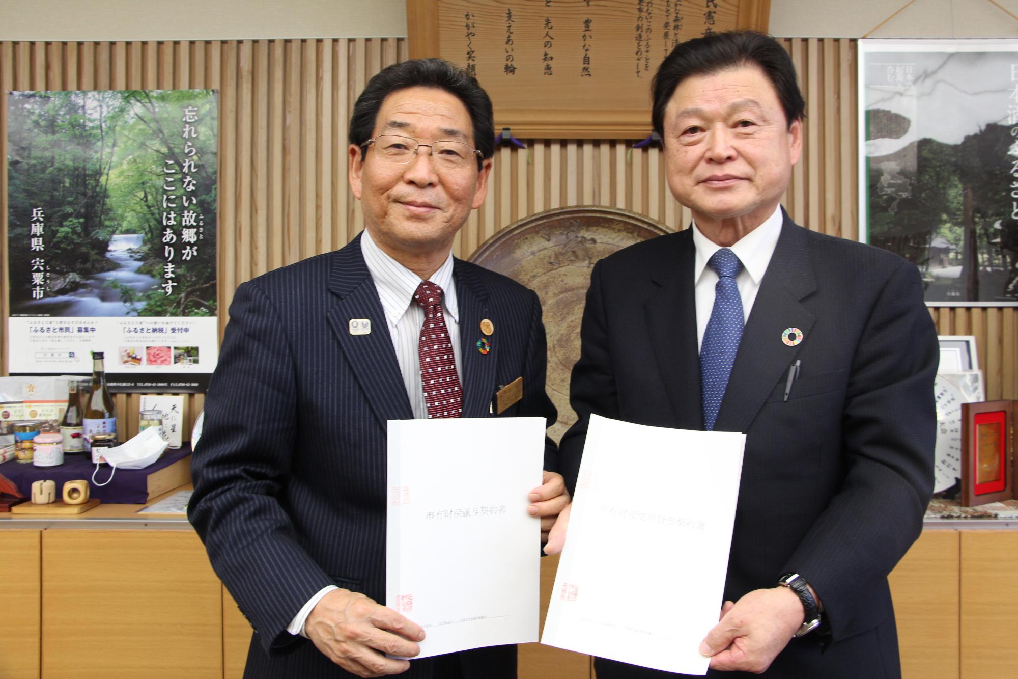 宍粟市長と秋武会長がそれぞれの手に契約書を持ち並んで立っている写真