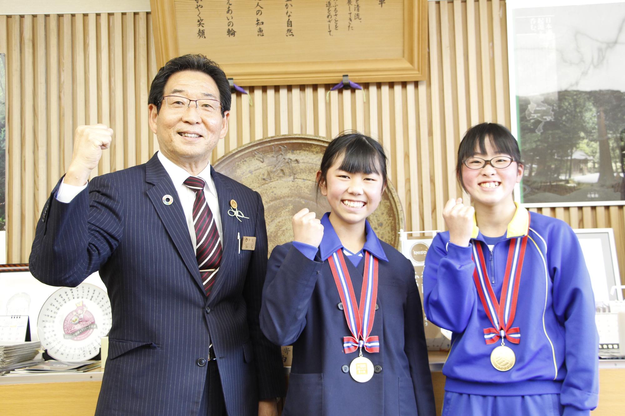 ジュニアオリンピックに出場する山本 陽さんと川上寧々さんが宍粟市長を表敬し、3人並んでガッツポーズで笑っている写真