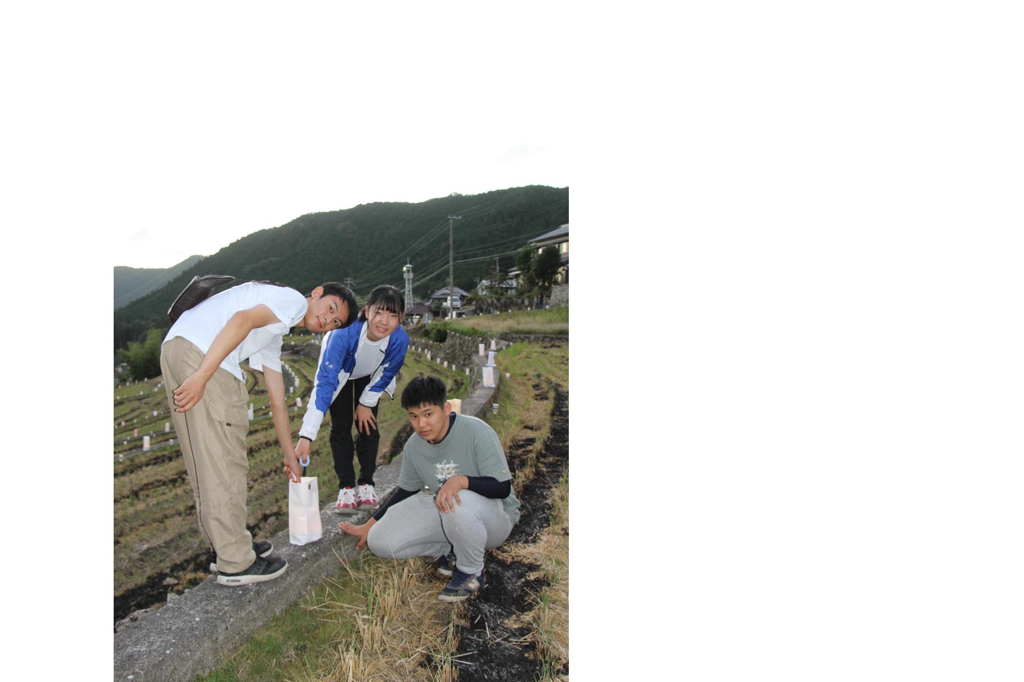 棚田の灯りの灯籠に火を灯す兵庫県立森林大学校の学生ら