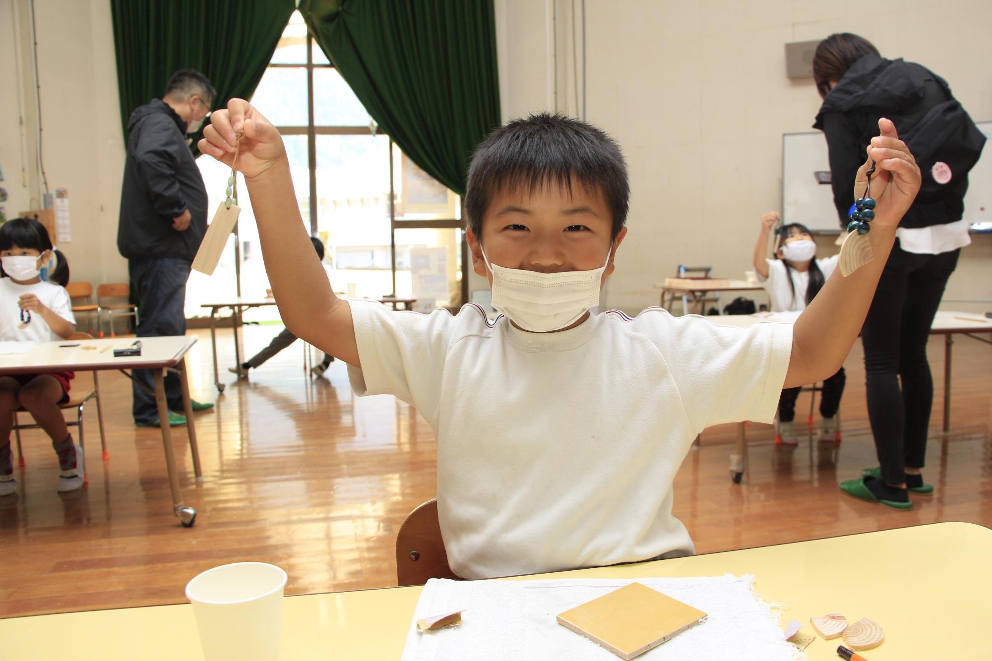 出来上がったキーホルダーを一つずつ持ち喜んで見せてくれている男の子の写真