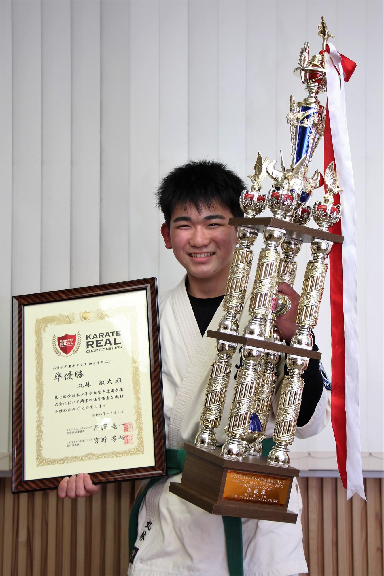 第7回全日本少年少女空手道選手権大会の準優勝トロフィーと賞状を手に笑顔を見せる丸林航大君の写真