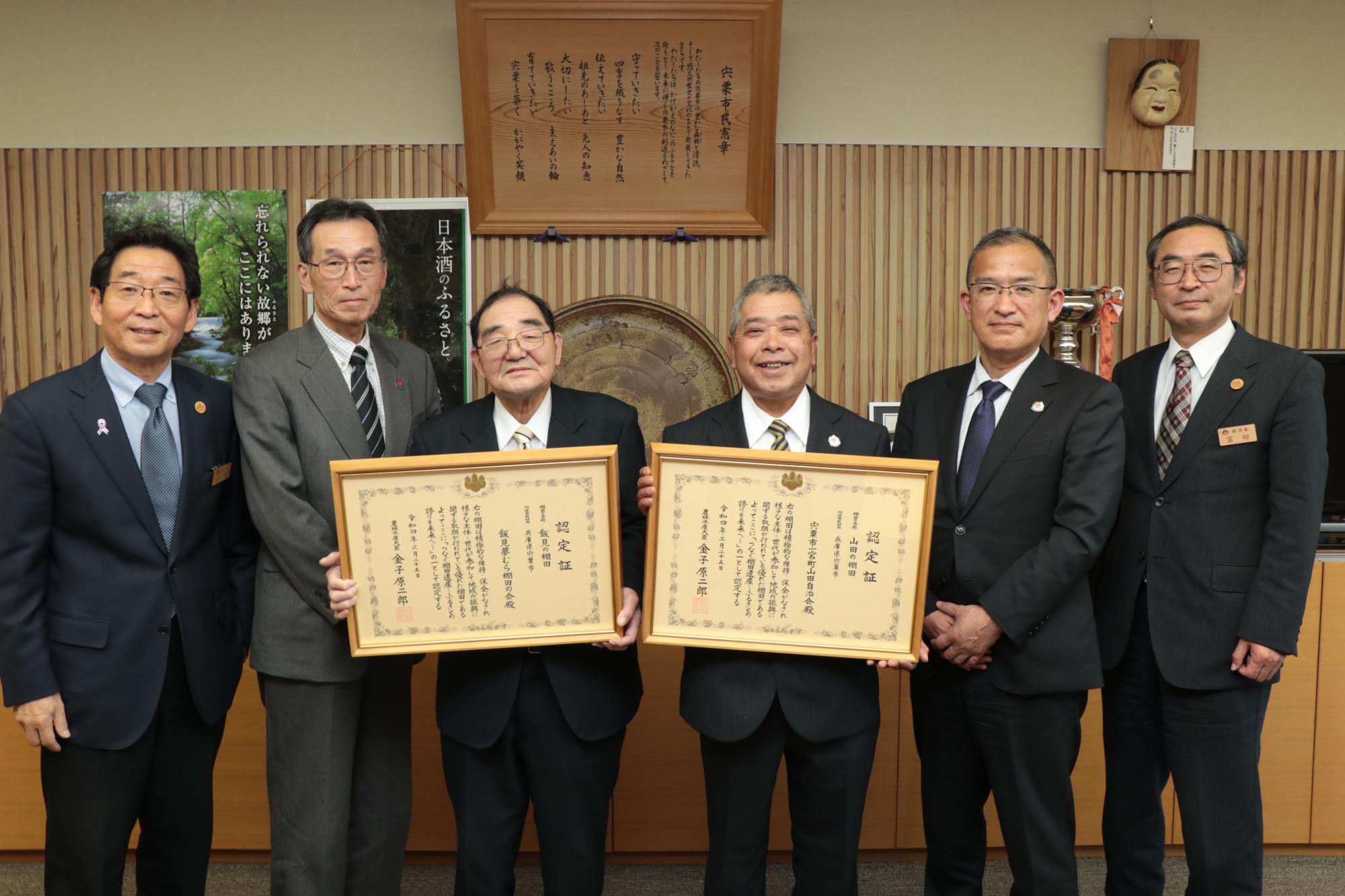 市長、副市長と横一列に並び農林水産省から受けたつなぐ棚田遺産の認定証を手に笑顔を見せる地元関係者の写真