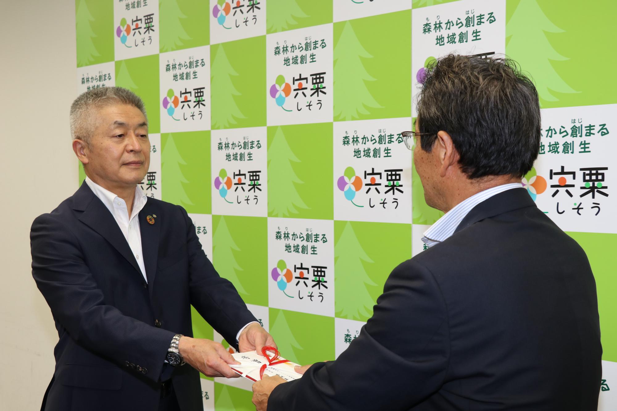 市役所で福元市長に目録を手渡す桑垣理事長の写真