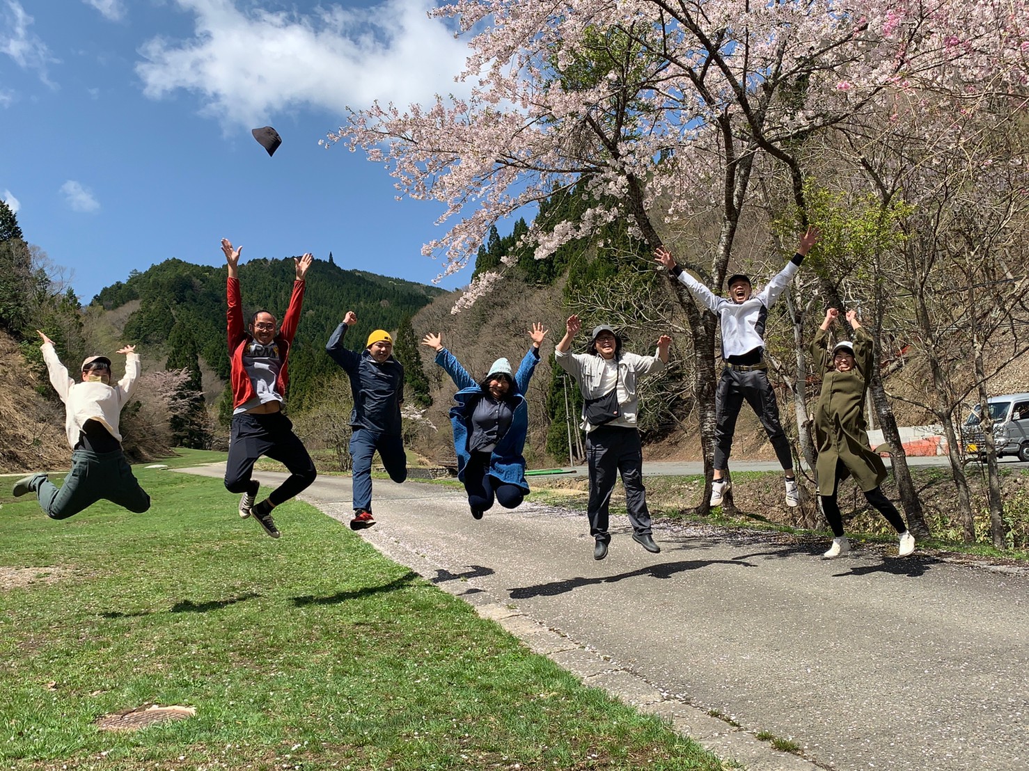 市内の桜をバックにジャンプしてアピールするしそくらメンバーらの写真