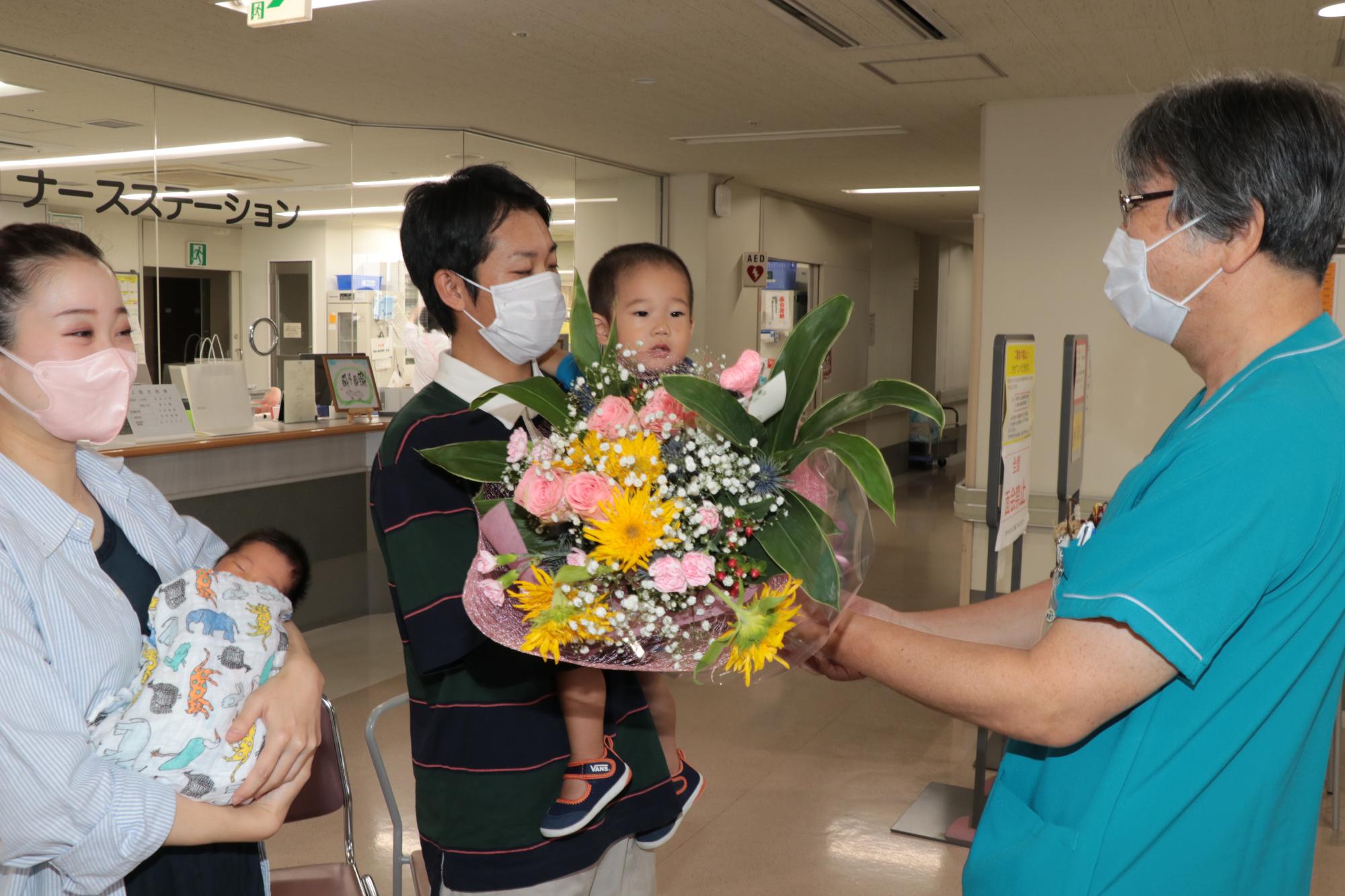 宍粟総合病院8千人目の赤ちゃん誕生記念に佐竹院長から花束を贈呈される石原さん夫婦の写真