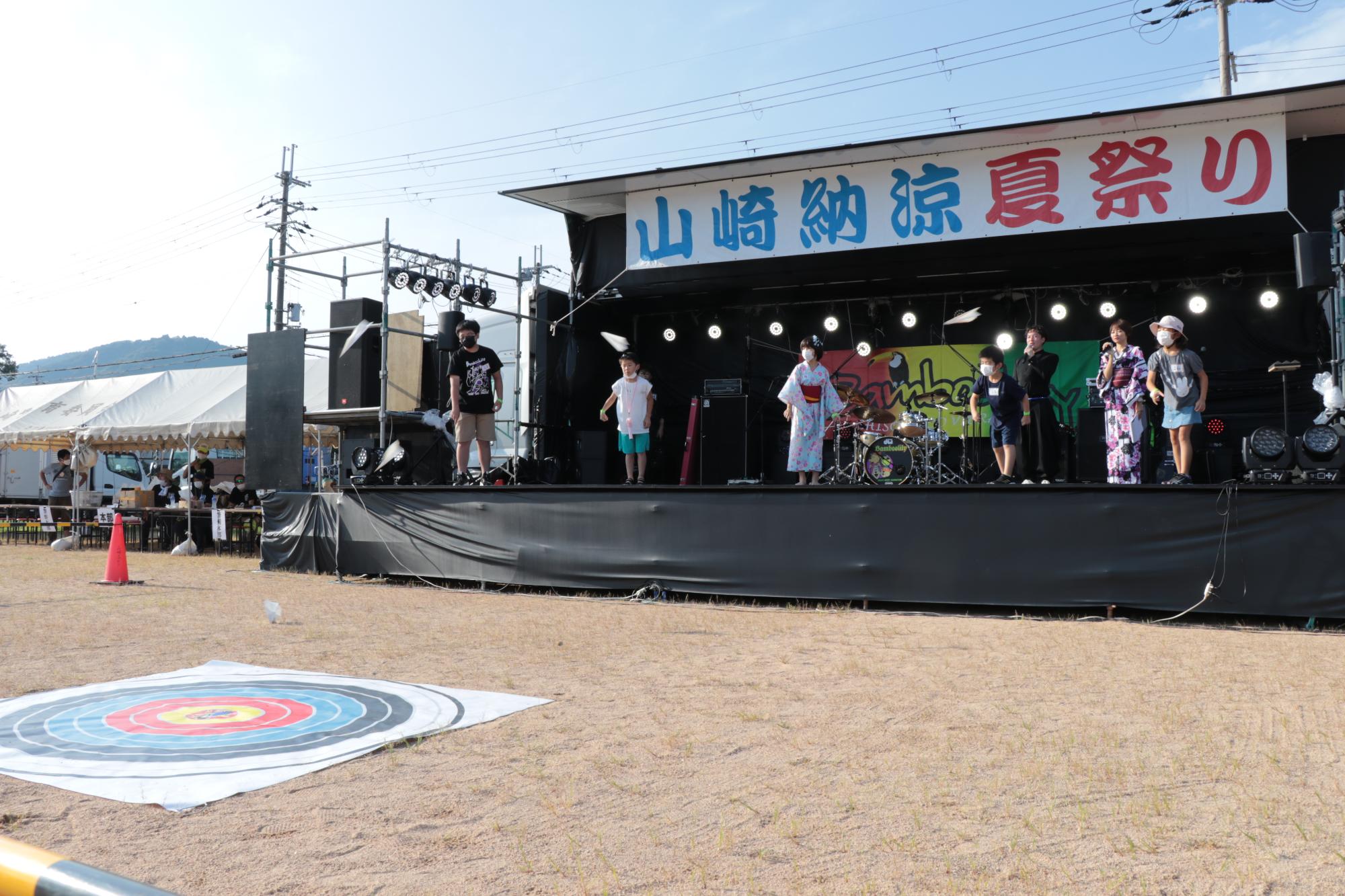 山崎納涼夏祭りで紙飛行機を飛ばして的を狙う競技を楽しむ参加者らの写真