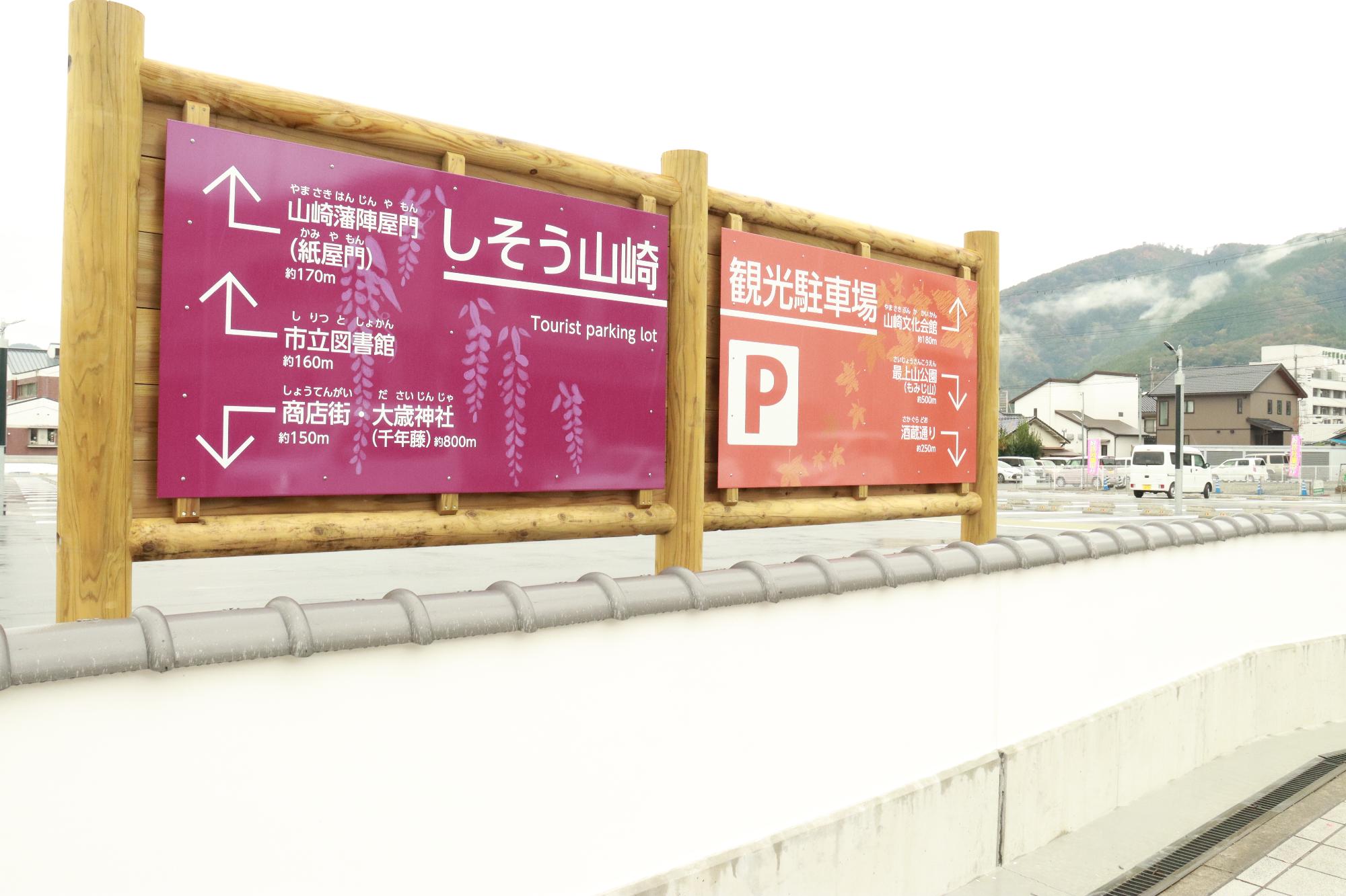 観光駐車場の県道側の敷地内に設置された観光駐車場と観光地までの距離を示す看板の写真