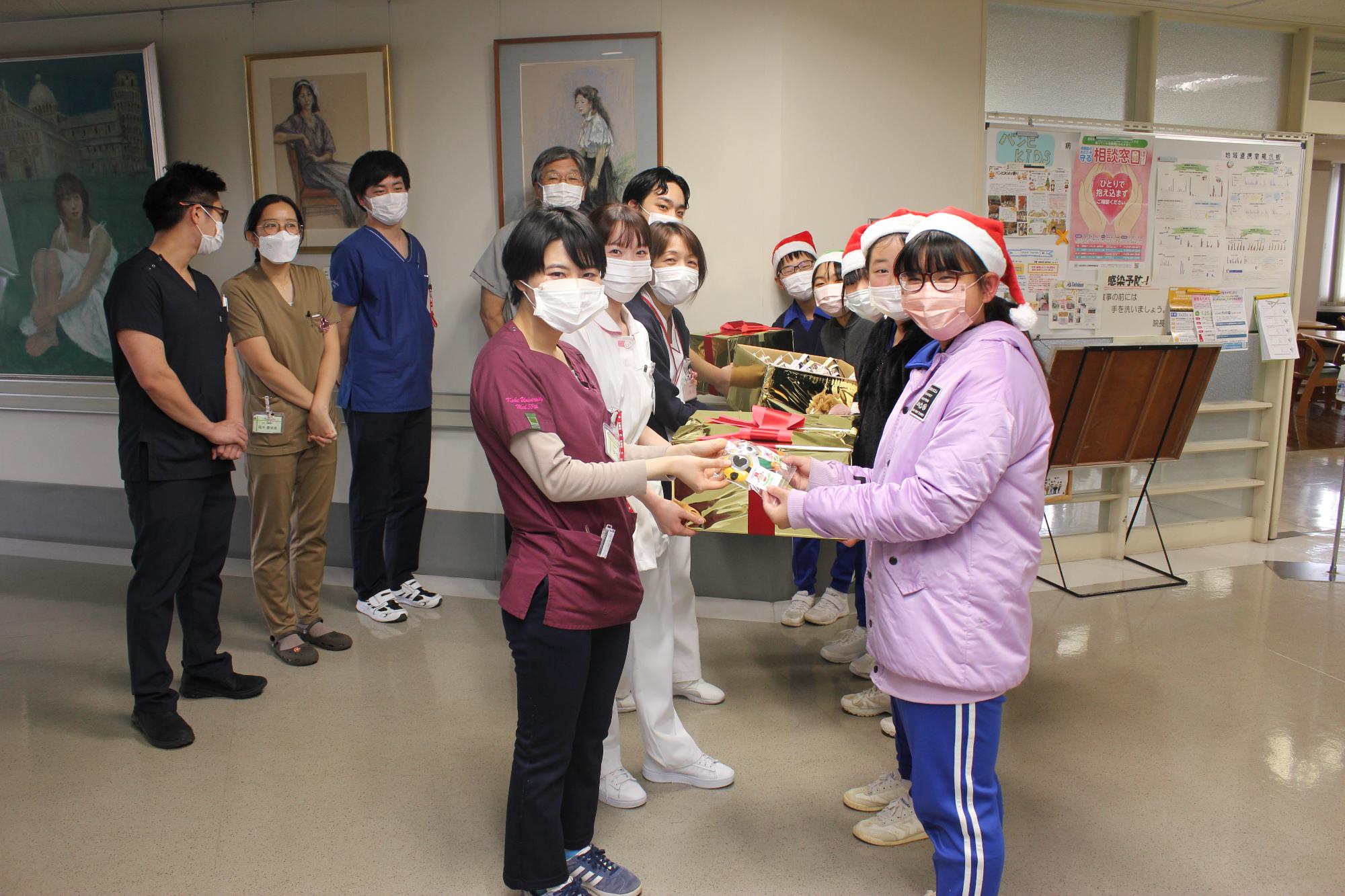 戸原小学校の児童らが宍粟総合病院のスタッフにパンジーの苗を手渡している写真