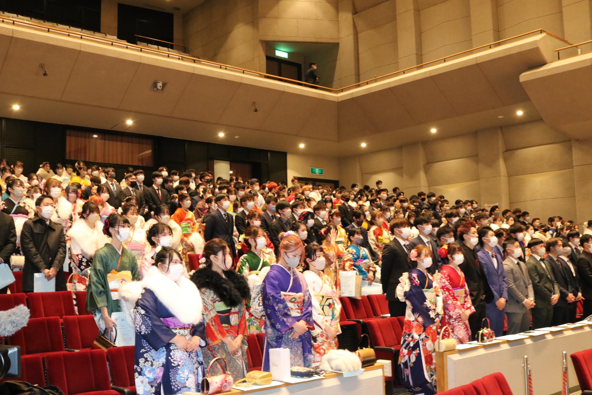 山崎文化会館ホールで式典に臨む20歳の新成人らが並んで立っている写真
