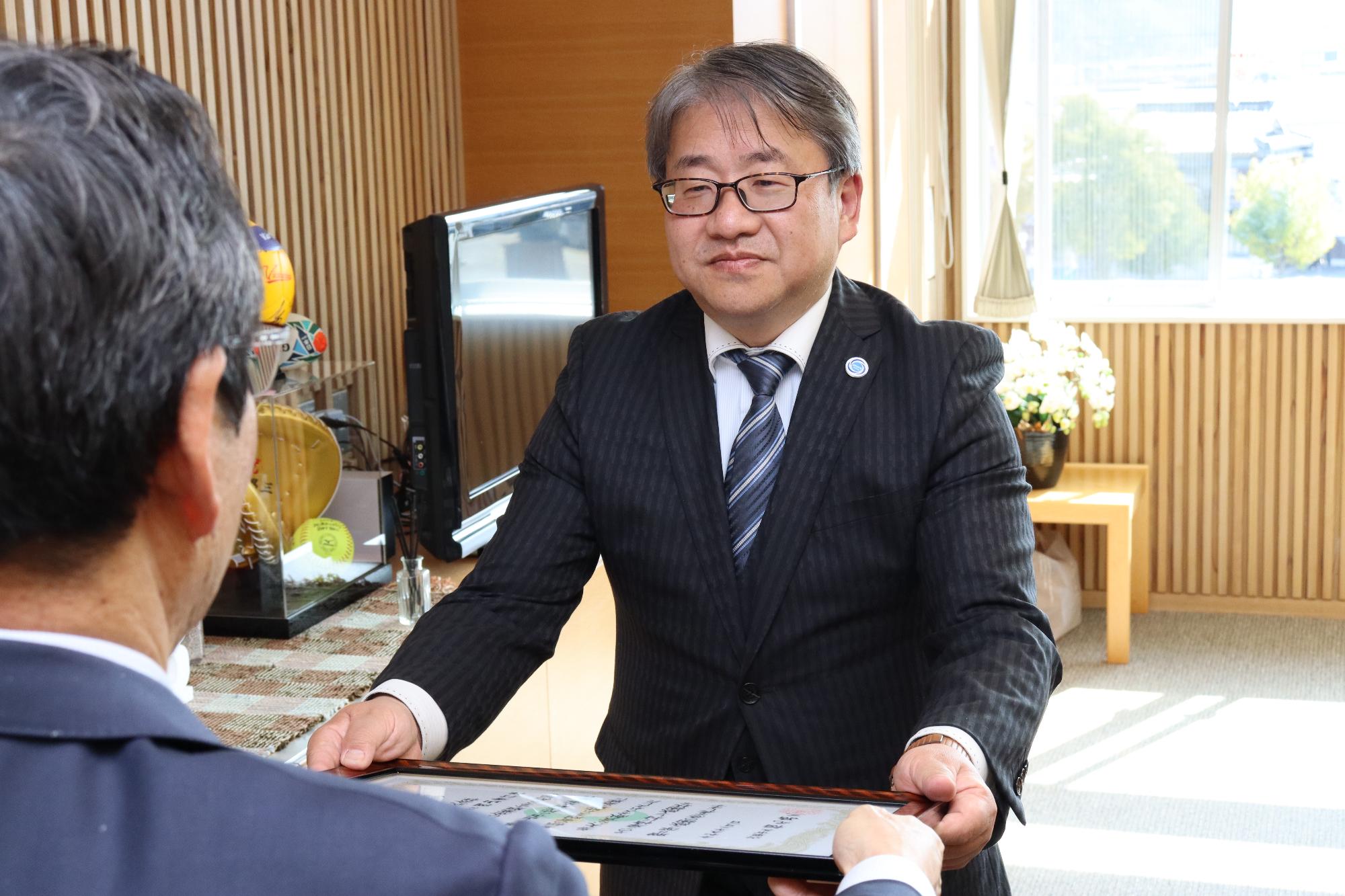 市長室で福元市長から感謝状を受け取る岡山秀行代表取締役の写真