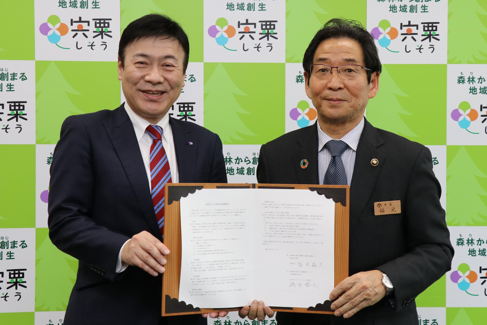 中外製薬の嶋内部長と福元市長が協定書を手に正面を向いている写真