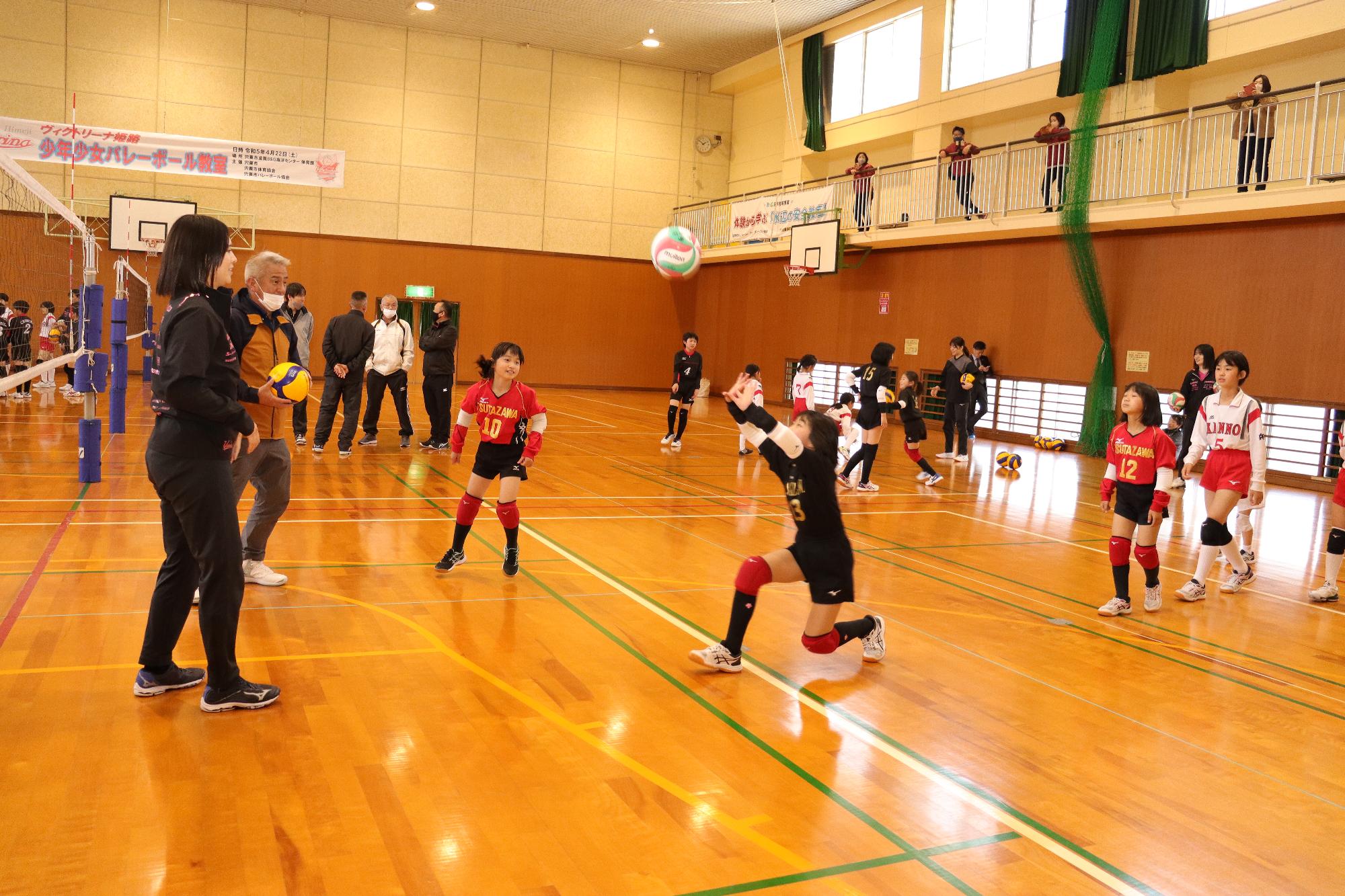 ヴィクトリーナ姫路の選手から参加した小学生らがボールをつかってレシーブやトスの指導を受けている写真