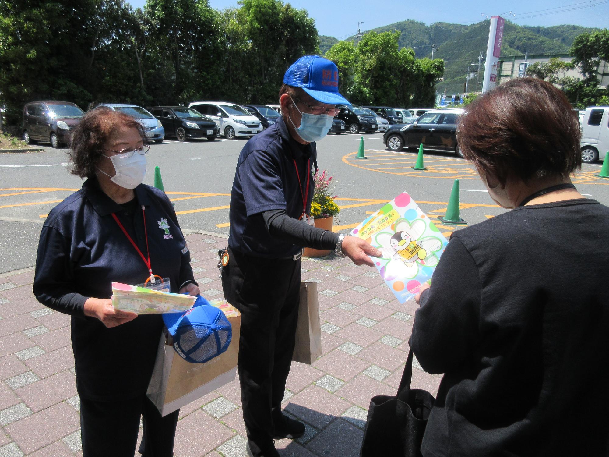 市の民生委員・児童委員がイオン山崎店の店内出入口周辺で客にチラシを配っている写真