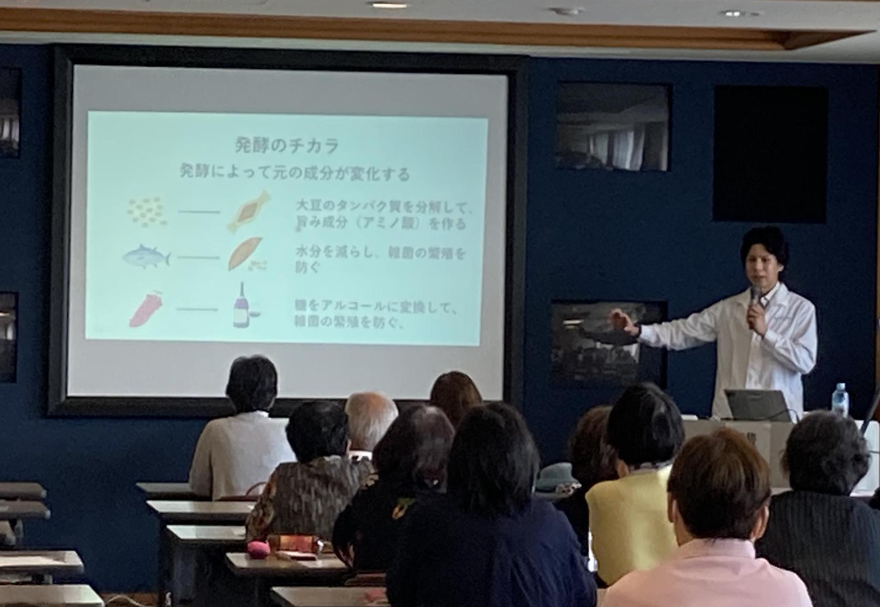 サントリー研究員の金川さんが「発酵のチカラ」と表示されたスライドの説明をしている写真