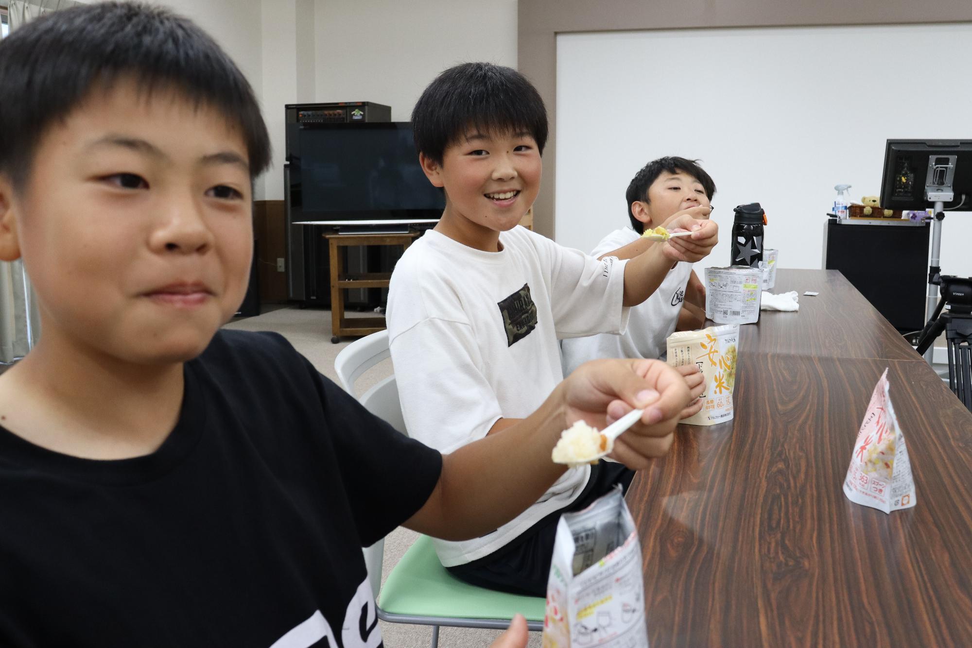 児童らが宍粟防災センターに備蓄されているアルファ化米を食べている写真