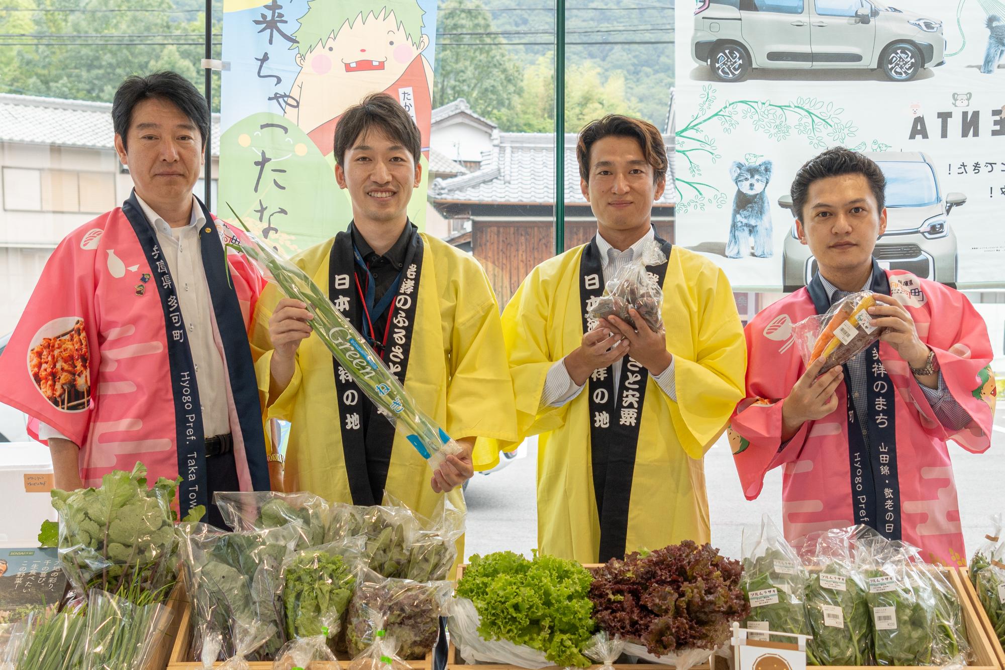 地域おこし協力隊の松下さんがトヨペット西脇店でほかのスタッフと並んで宍粟産の野菜をPRしている写真