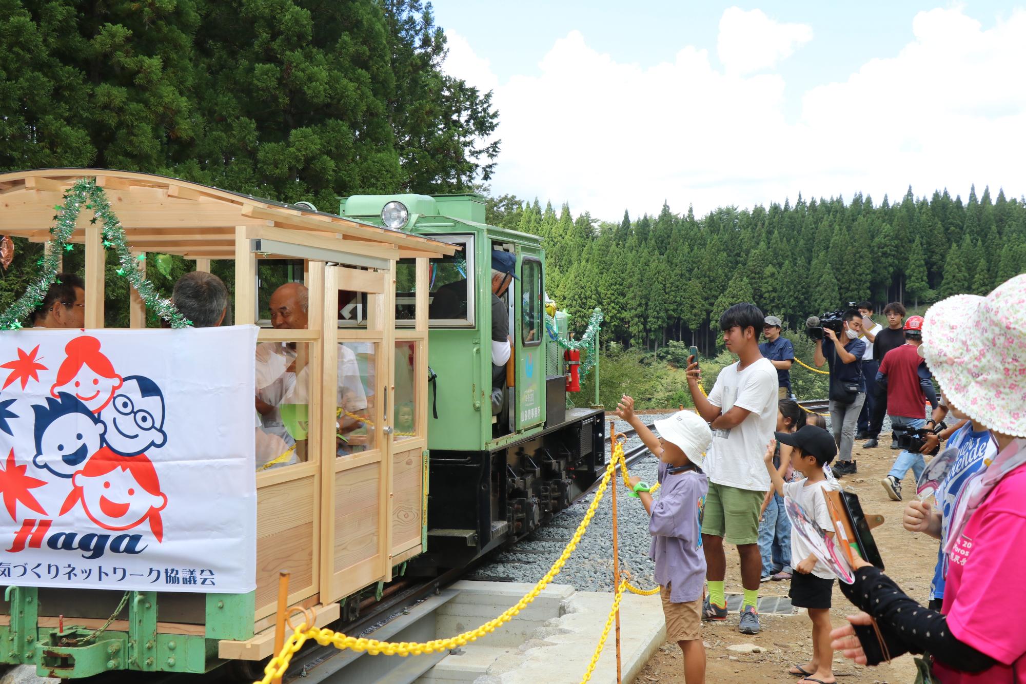 イベントに参加した子どもたちや関係者らが見守る中、完成した周回コースで試運転のため機関車を走らせている写真