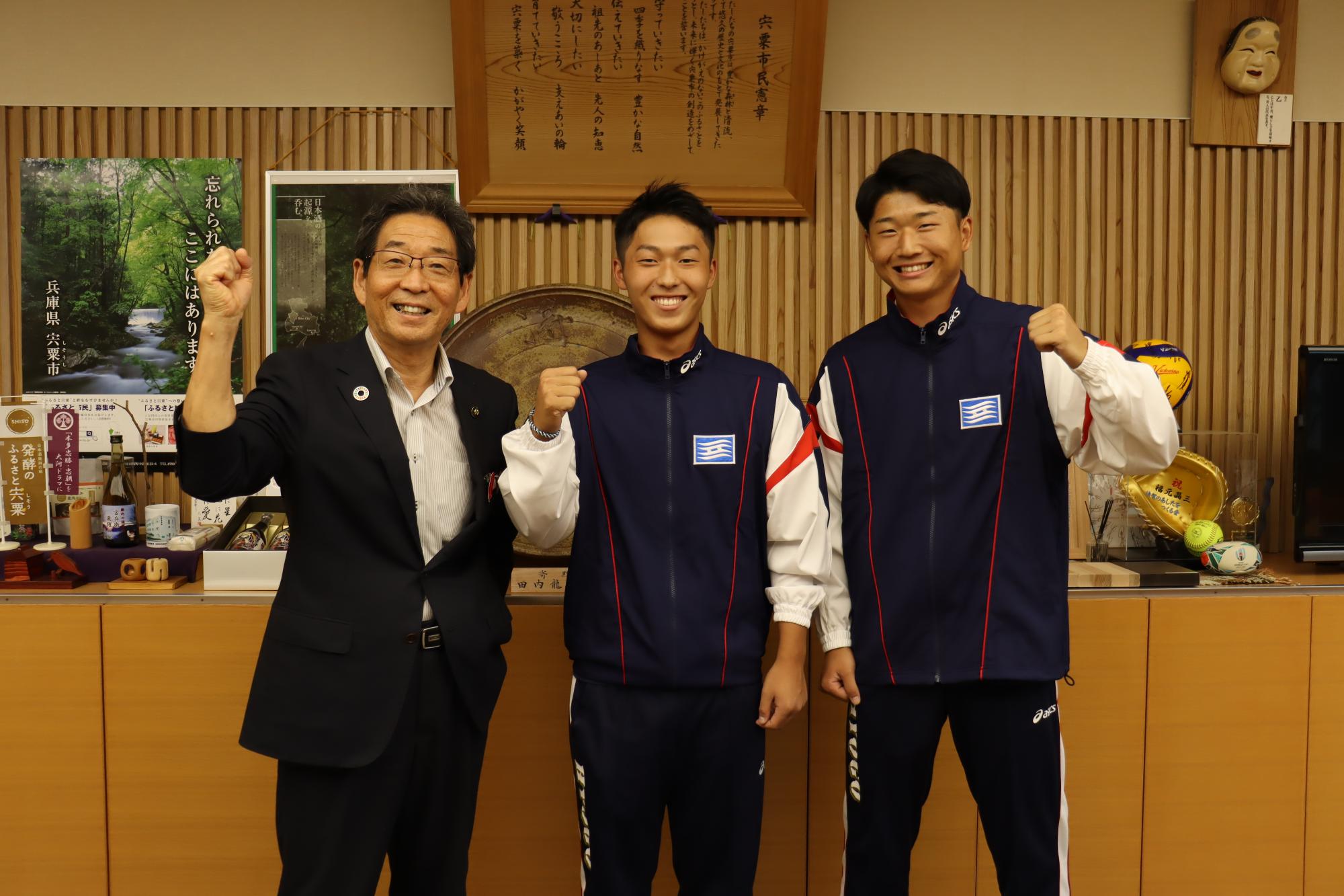 左から順に福元市長、中川さん、早川さんが市長室でガッツポーズをして並んで立っている写真