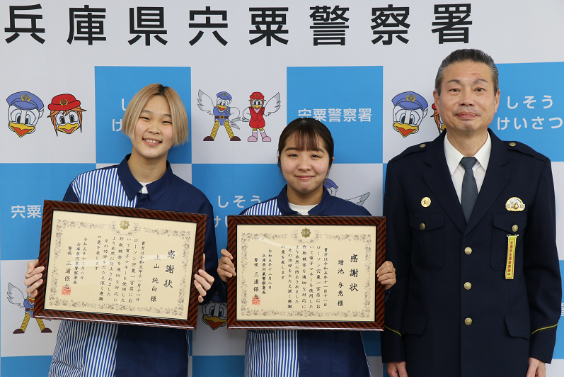 宍粟警察署で感謝状を持ったコンビニ店員の上山さん、増池さんが署長と1列に並び、笑顔を見せている写真