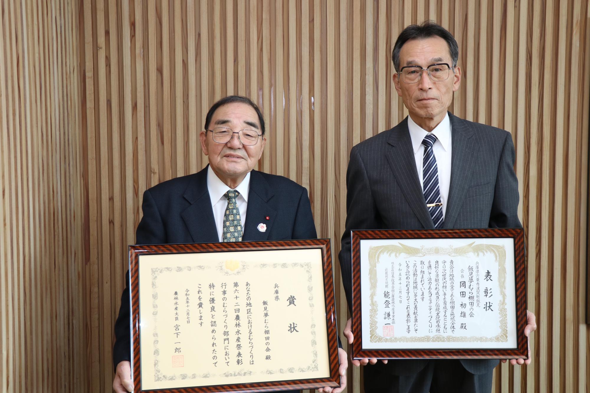 宍粟市役所で飯見夢むら棚田の会の岡田初雄会長と大柿直記さんが横に並んで表彰状を1枚ずつ持っている写真