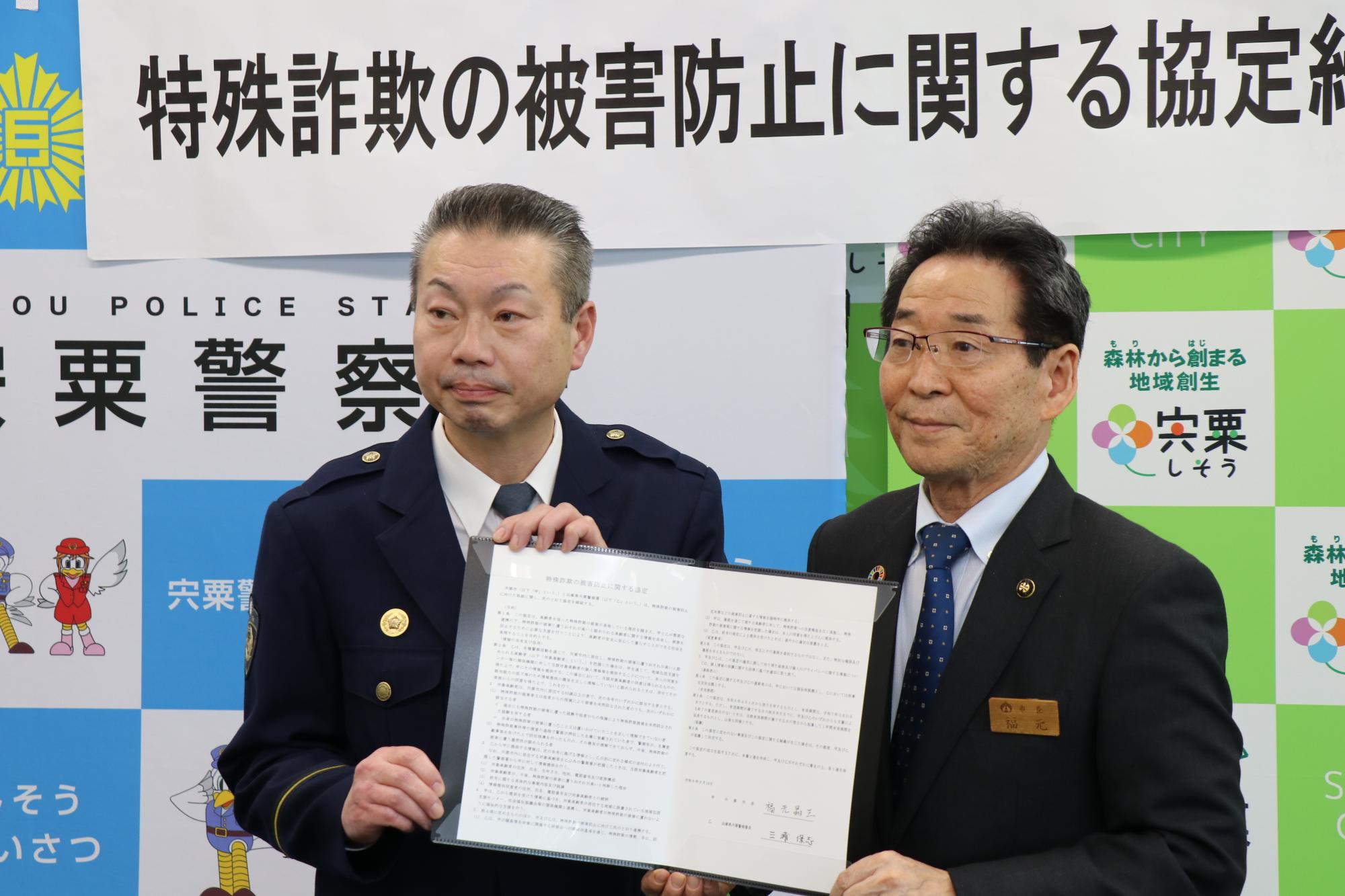 宍粟警察署の三浦署長と福元市長が署名した協定書を両側から手にもち、撮影に応えている写真