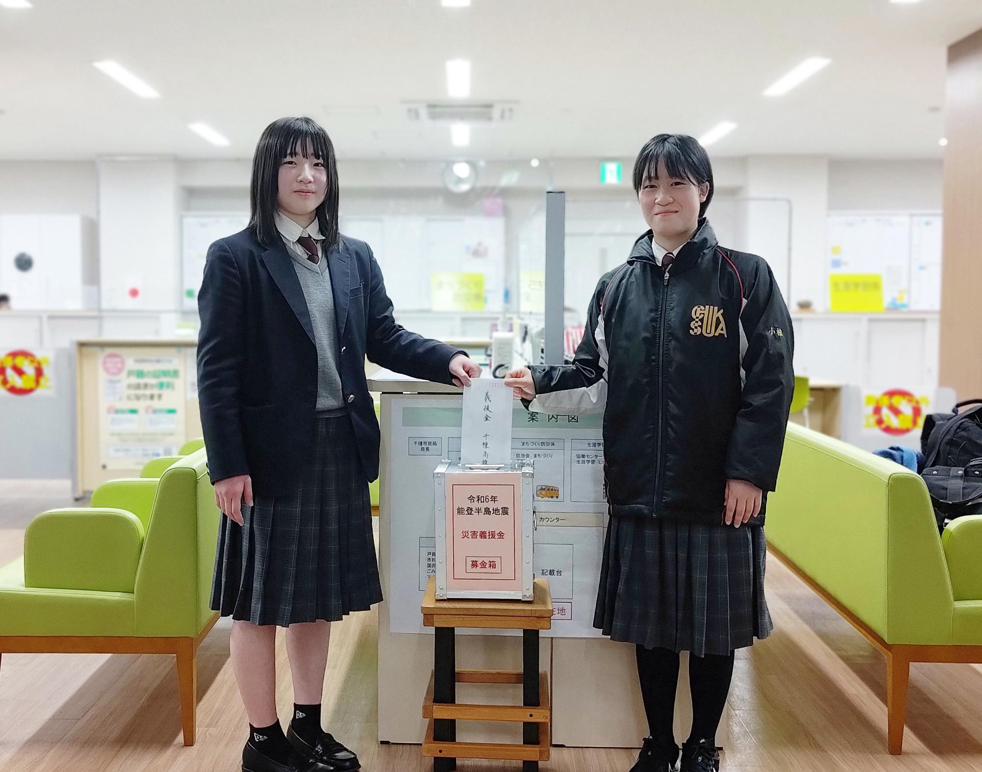 千種高校2年の小椋さんと平瀬さんが持参した能登半島地震への寄付金をライブリーちくさにある募金箱に入れている写真