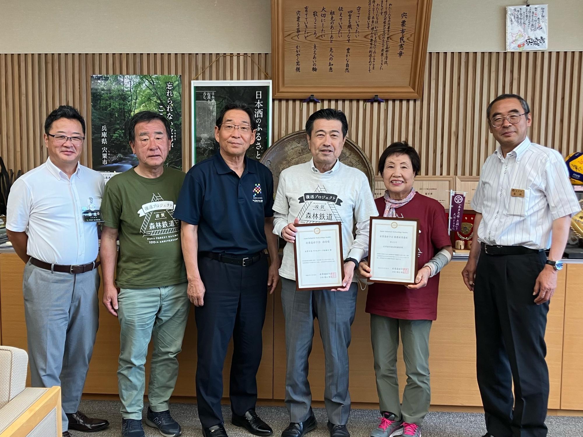市長表敬に訪れた波賀元気づくりネットワーク協議会のメンバーらと福元市長、富田副市長が並んで立っている写真