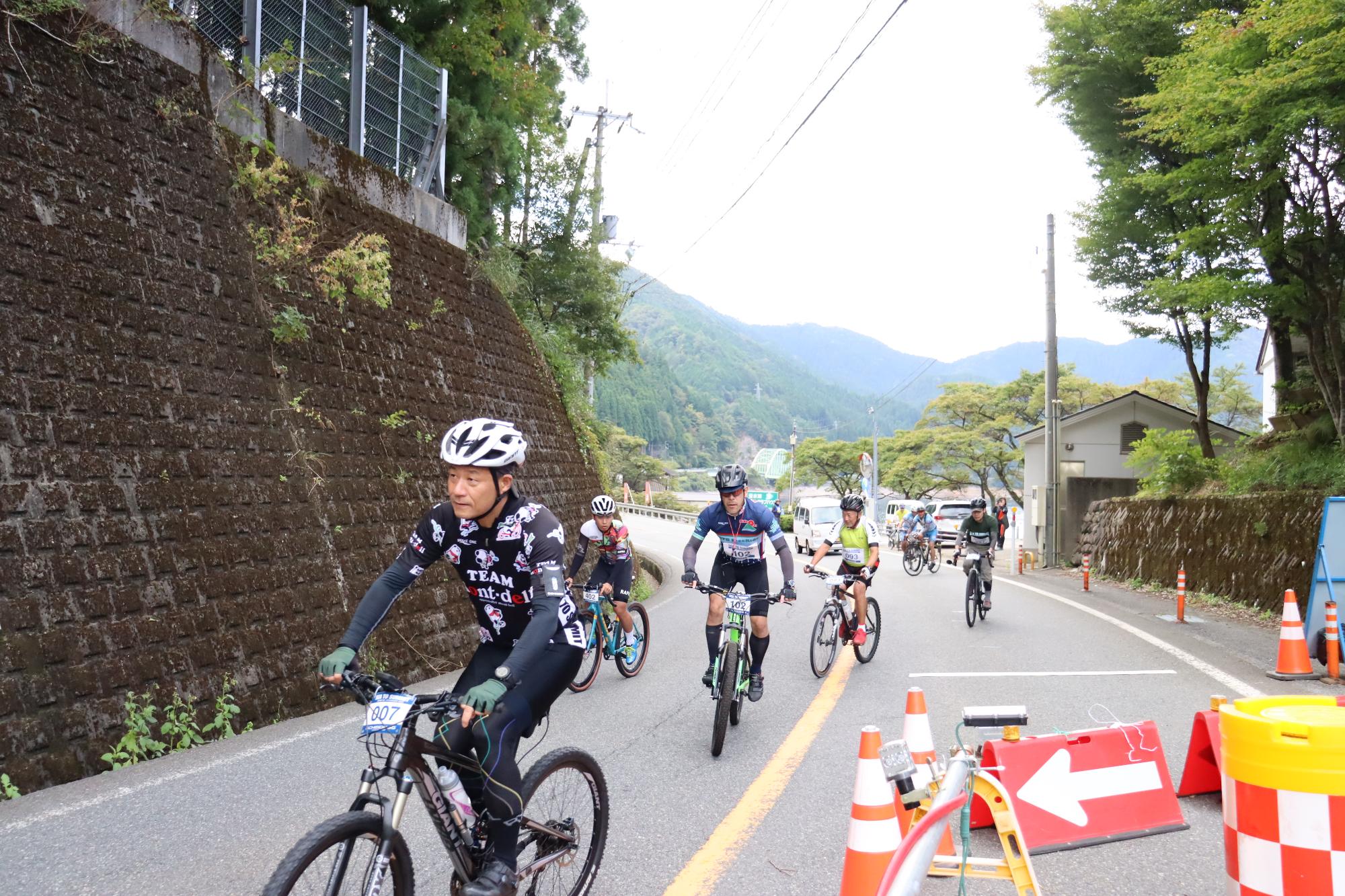 カヤックから自転車に乗り換えた参加者が、片側通行になっている工事個所を避けて国道29号を続々とスタートしている写真