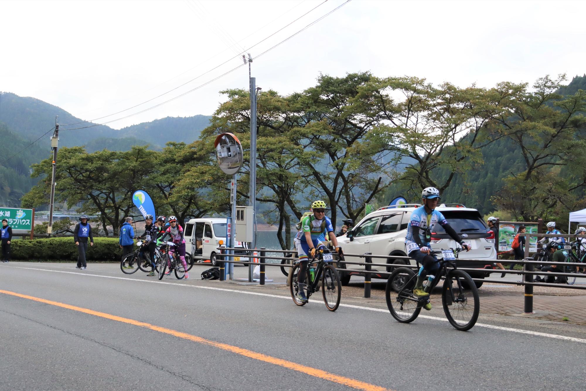 カヤックから自転車に乗り換えた参加者が音水湖カヌークラブハウス前から車道を確認しながら国道29号に出て走行し始めている写真
