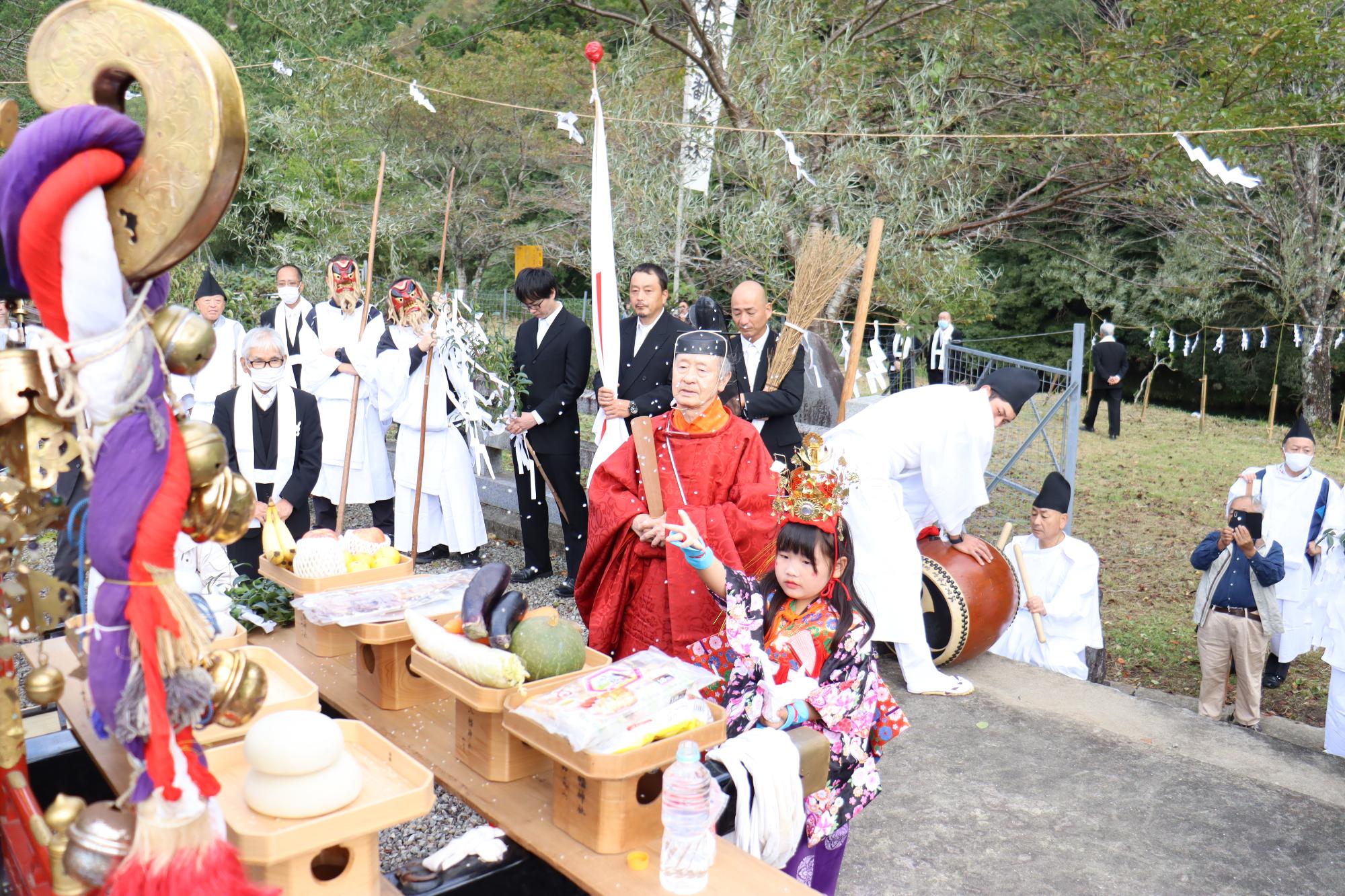 御旅所で神輿に参拝する少女神子が持参した米を投げている写真