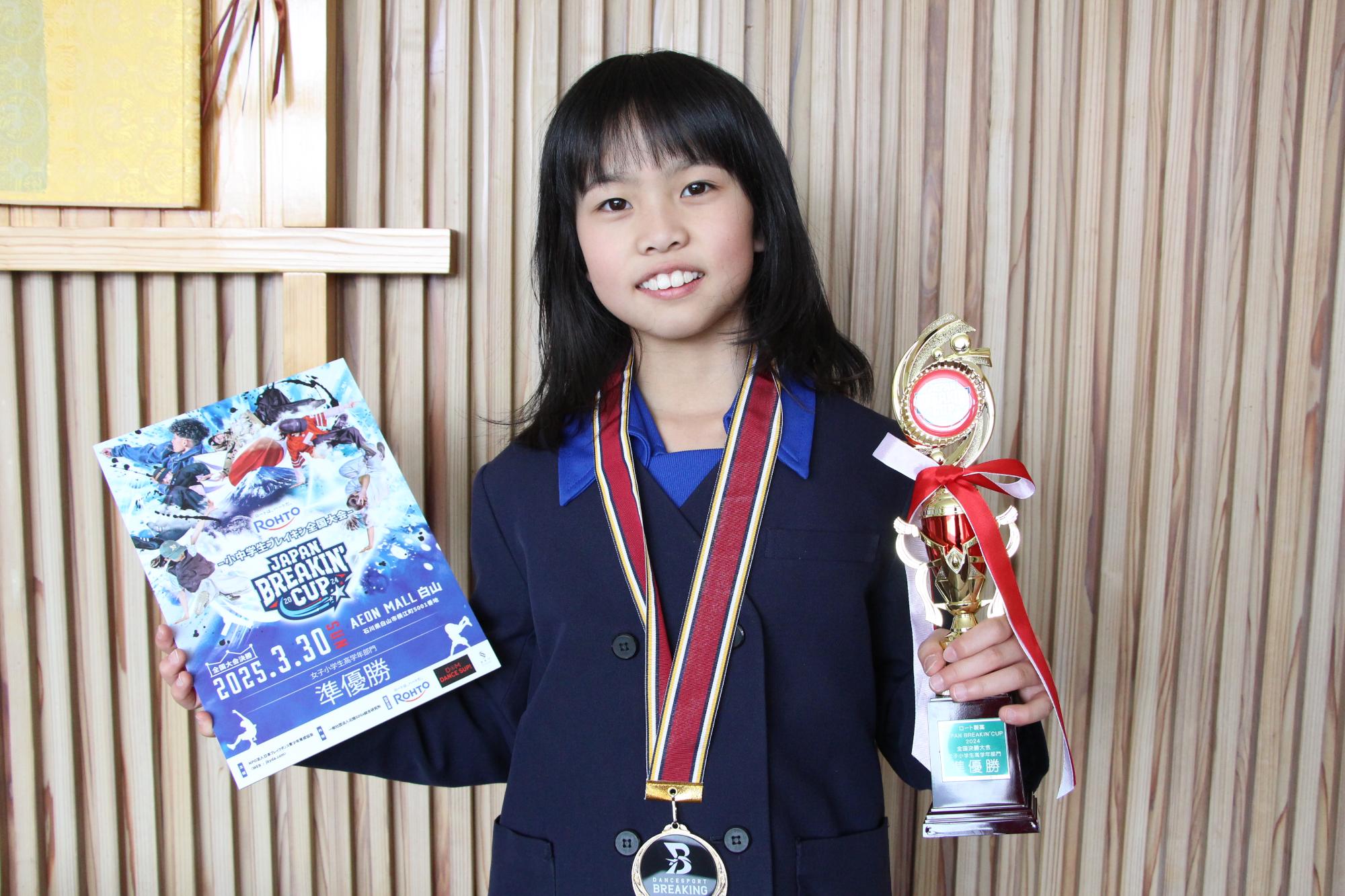 準優勝のトロフィー、ボードを手に笑顔を見せる宇田さんの写真
