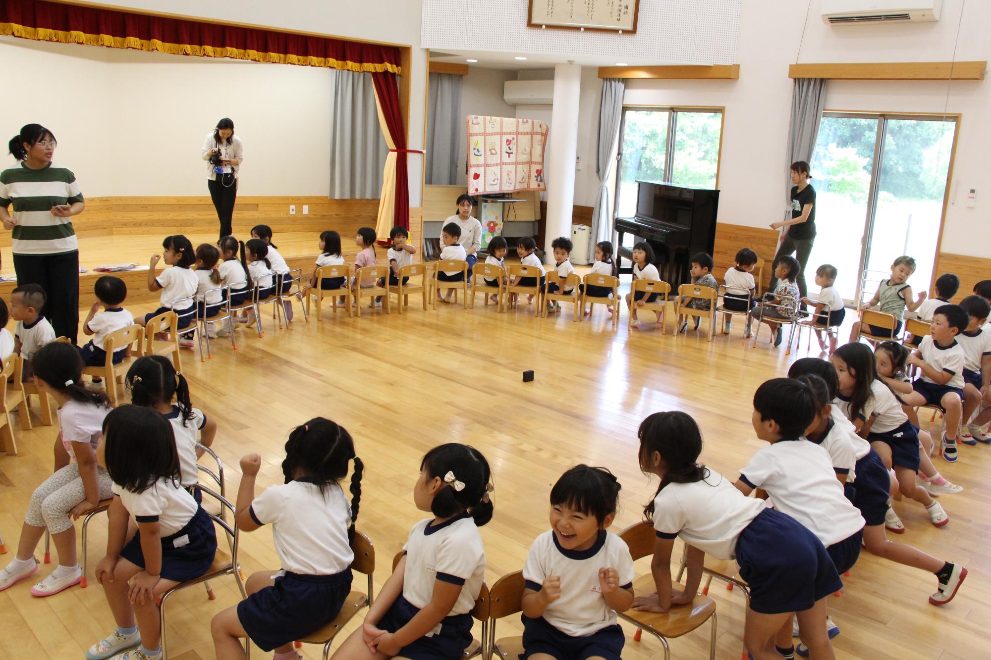 戸原こども園の園児らが椅子に座って、輪になり話を聞いている様子