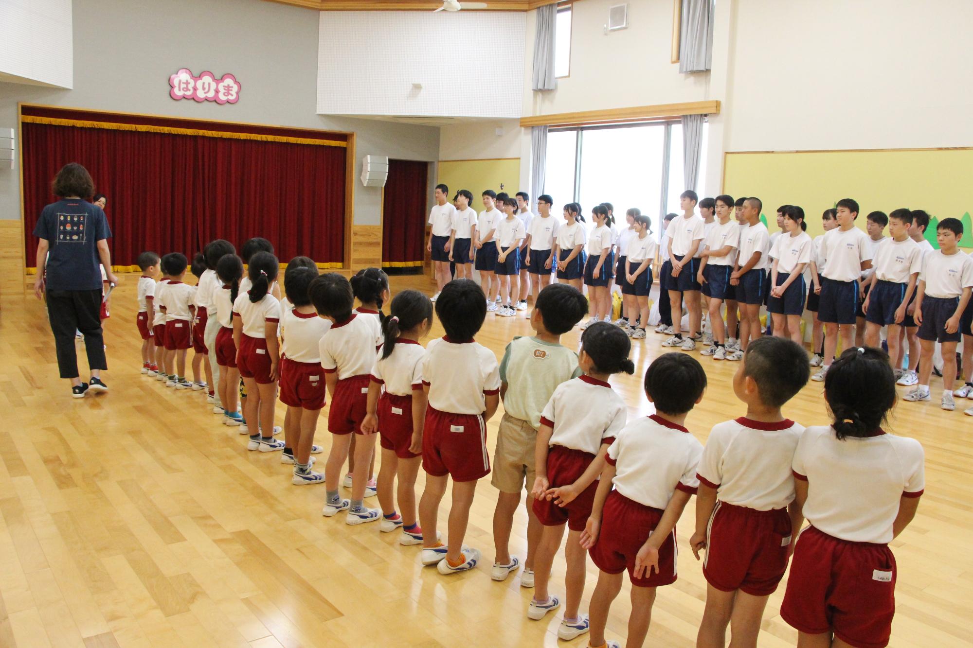 はりま一宮こども園の園児と一宮南中の生徒が交流行事で横一列に並び、向かい合っている様子