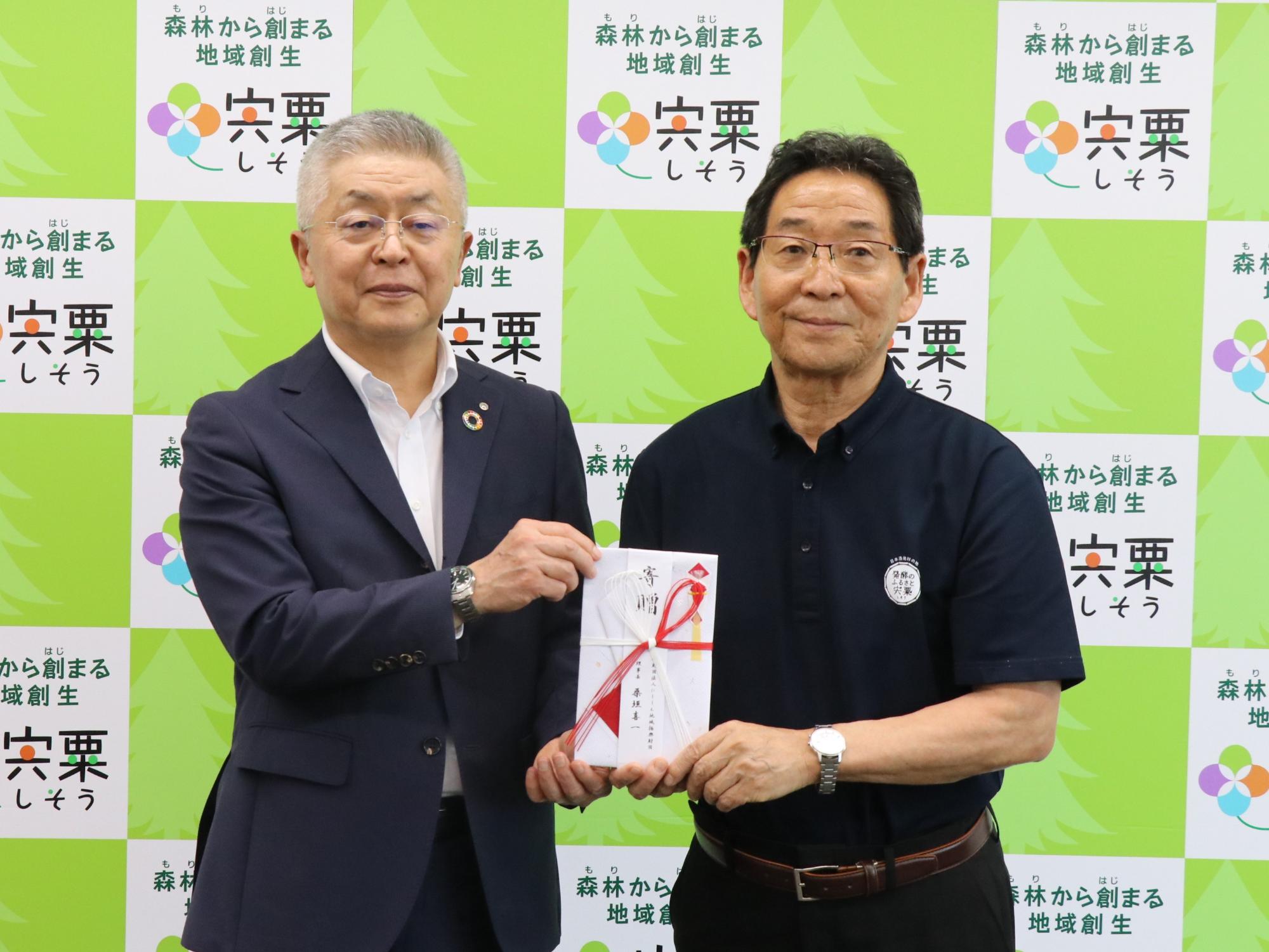 図書券贈呈式で福元市長（右）に目録を渡すにししん地域振興財団 桑垣理事長（左）