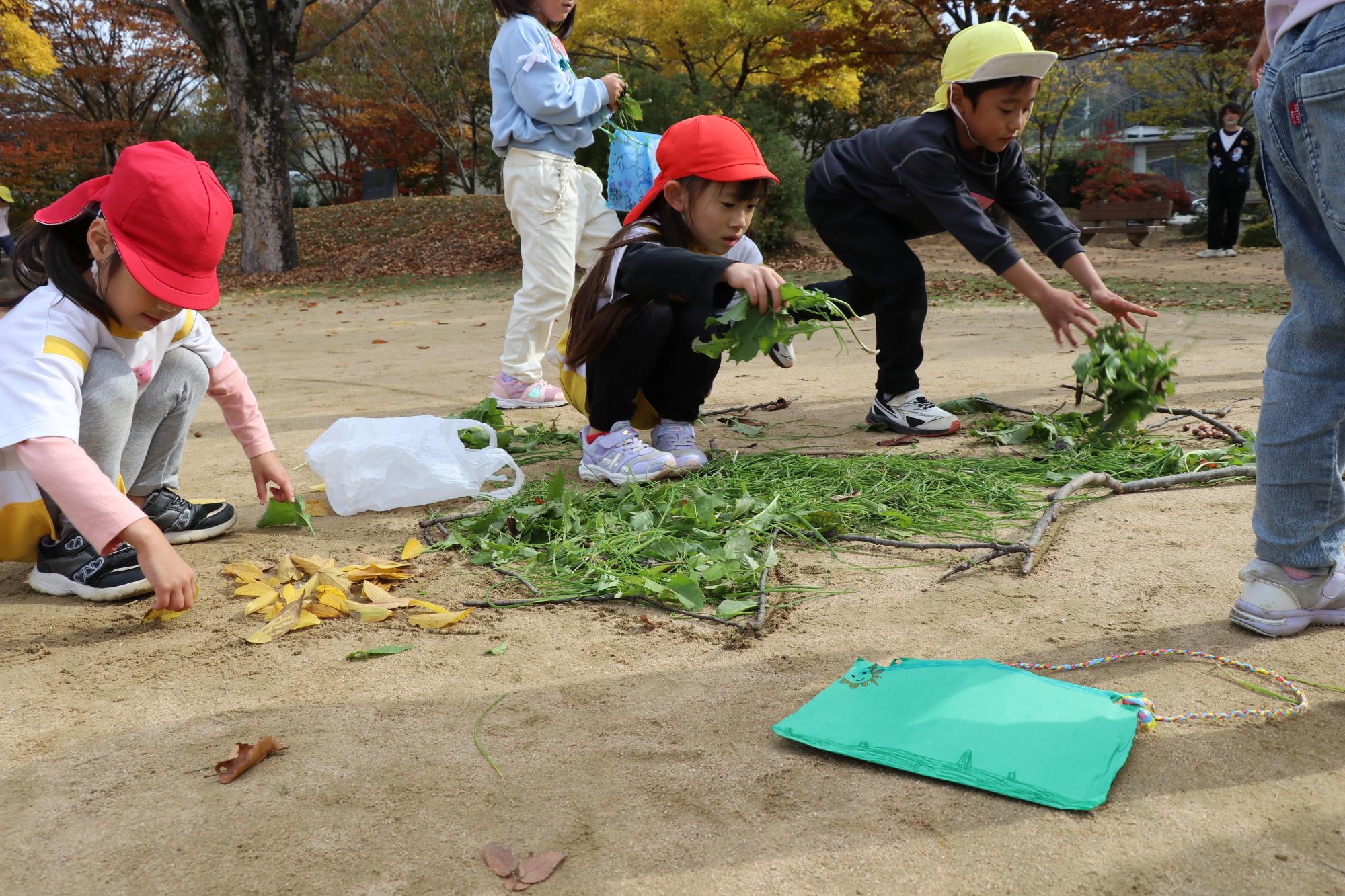 集めた落ち葉や草でクリスマスツリーを作っている園児たち