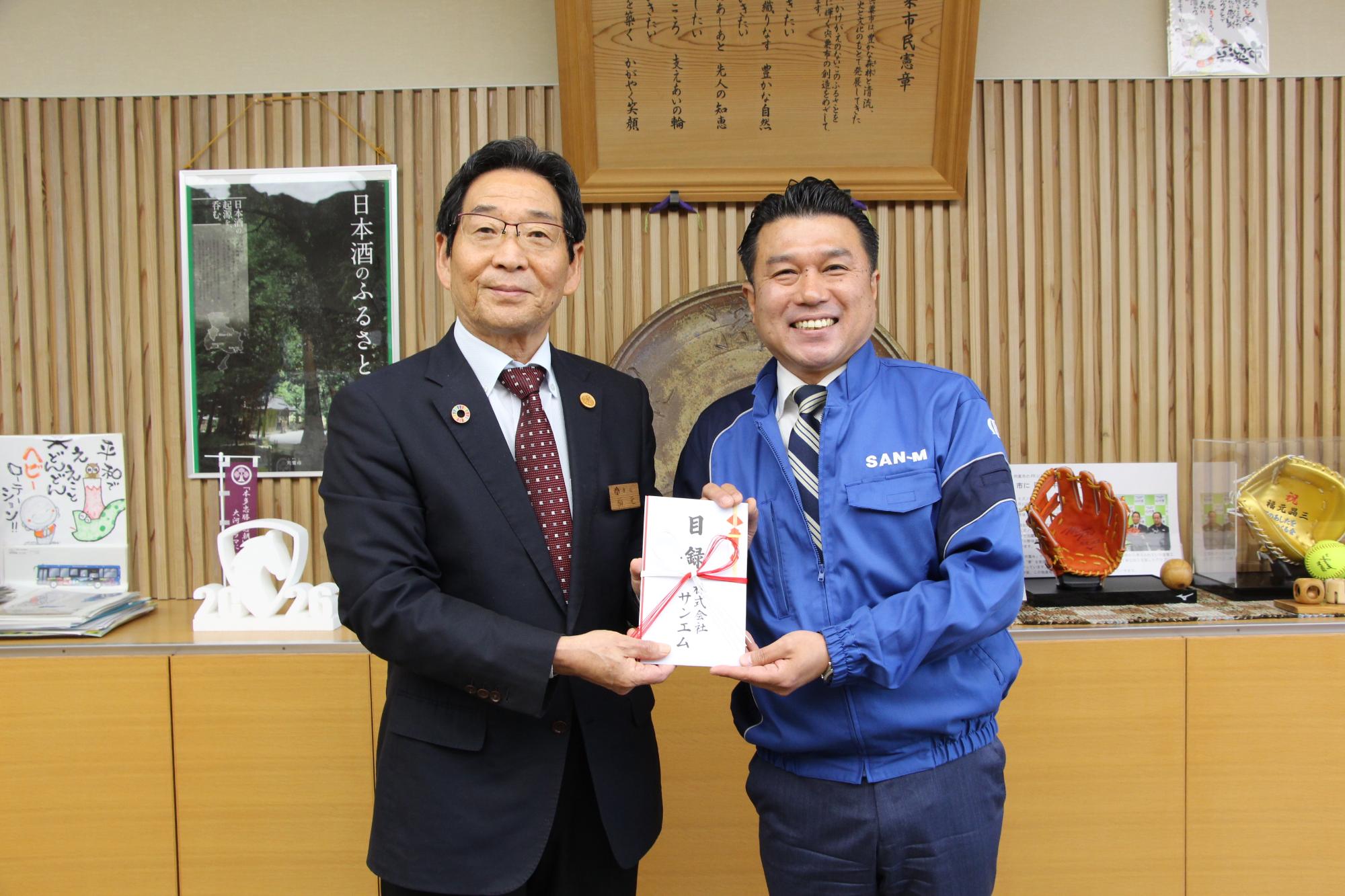 市長が株式会社サンエムの代表者から寄付を受け取っている様子