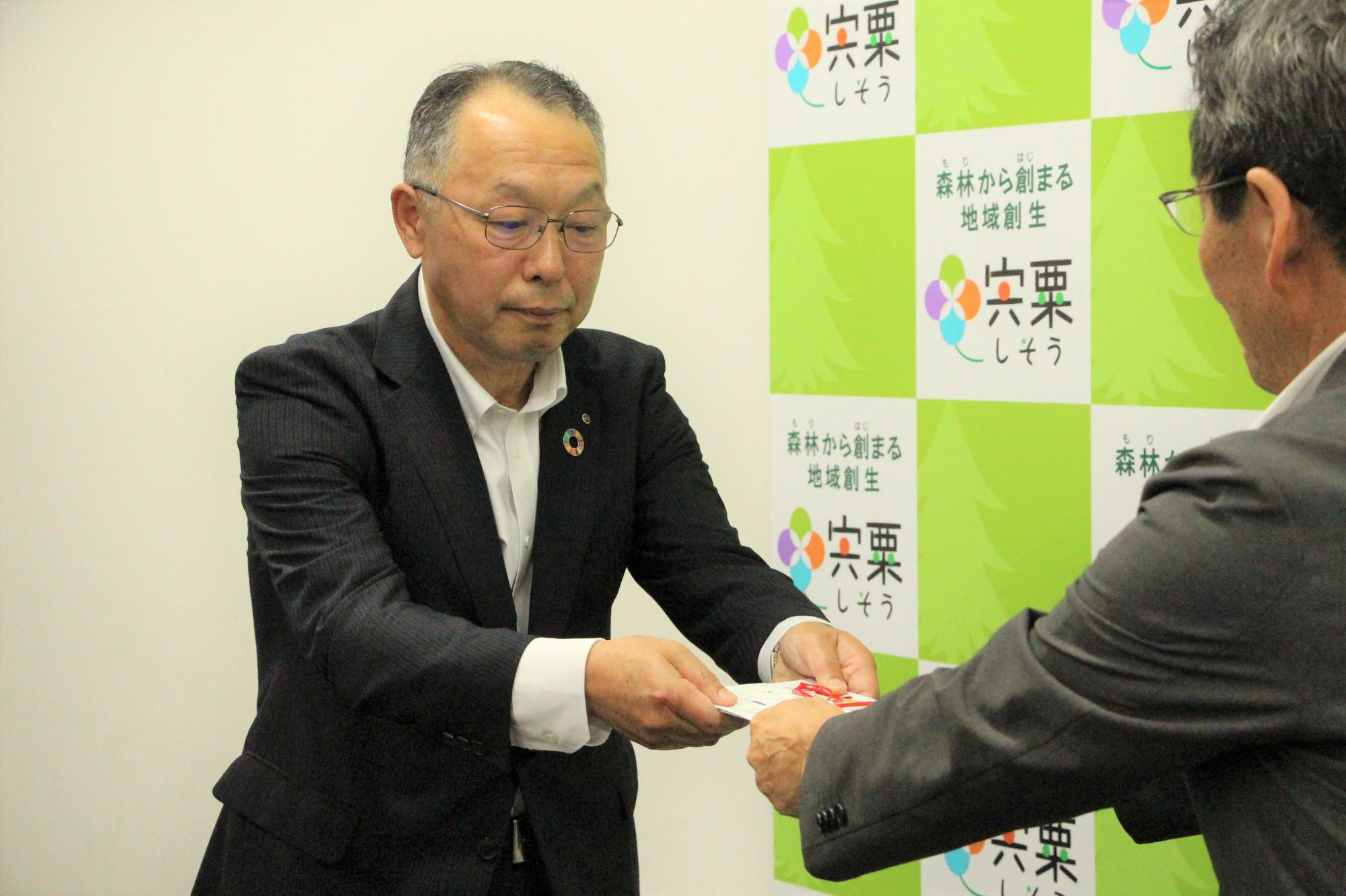 図書カード贈呈式で福元市長（右）に目録を渡す、西兵庫信用金庫 平山常務理事（左）