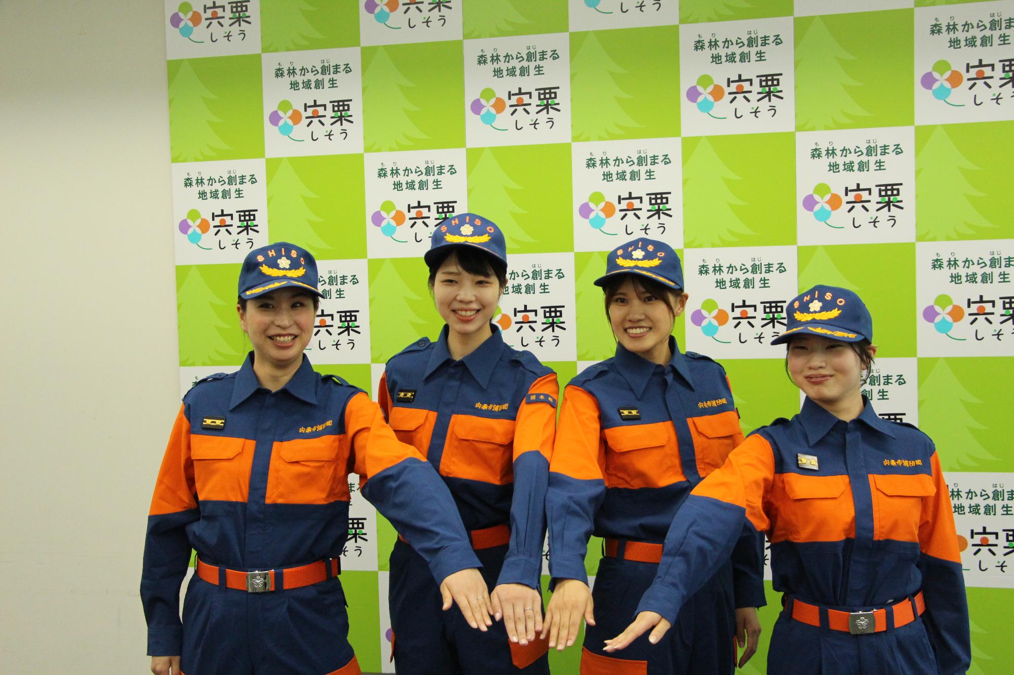 手を重ねて意気込む女性消防団員4人の写真