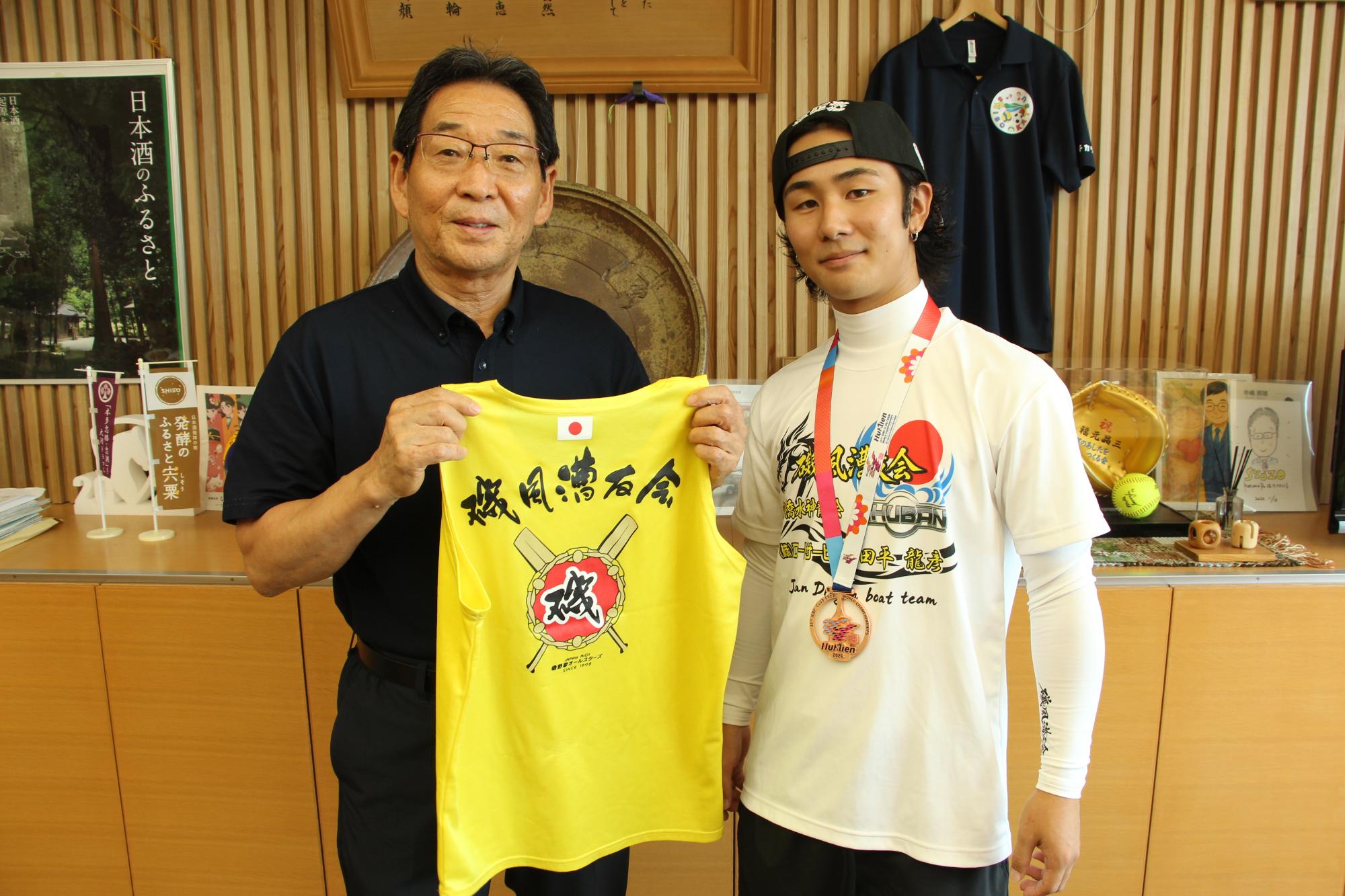 ユニフォームを持った市長とメダルをかけた柴原さんが横に並んでいる記念写真