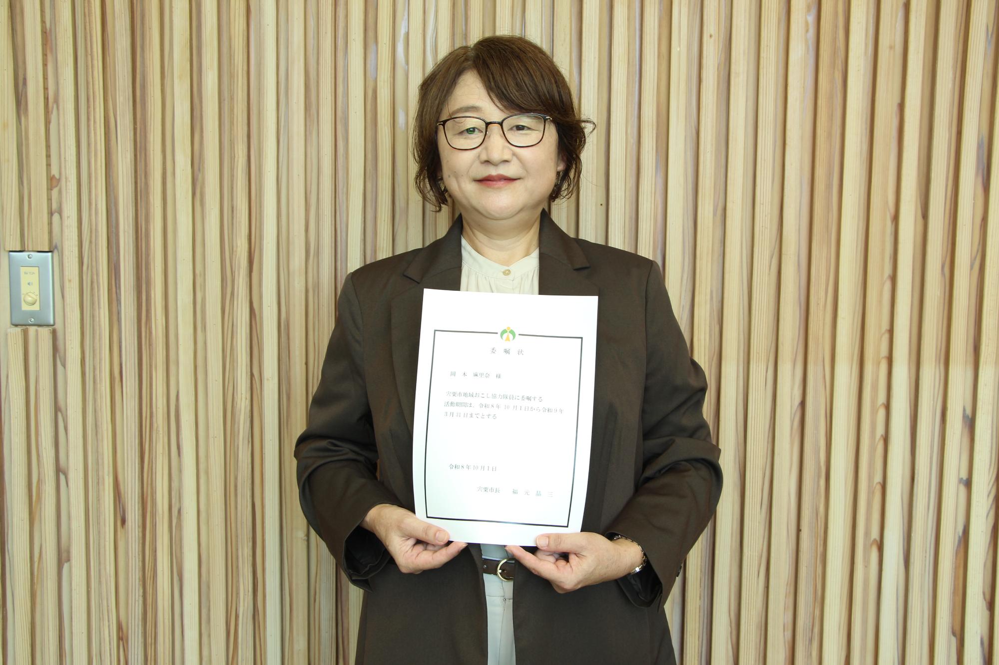 委嘱状をもって微笑む岡本さん