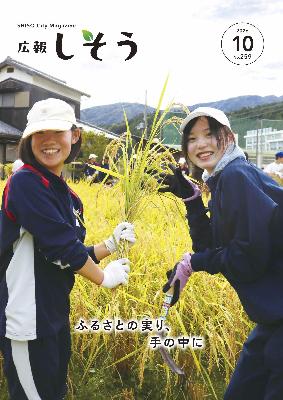 広報10月号：稲を持った二人の学生が笑顔で映っている姿
