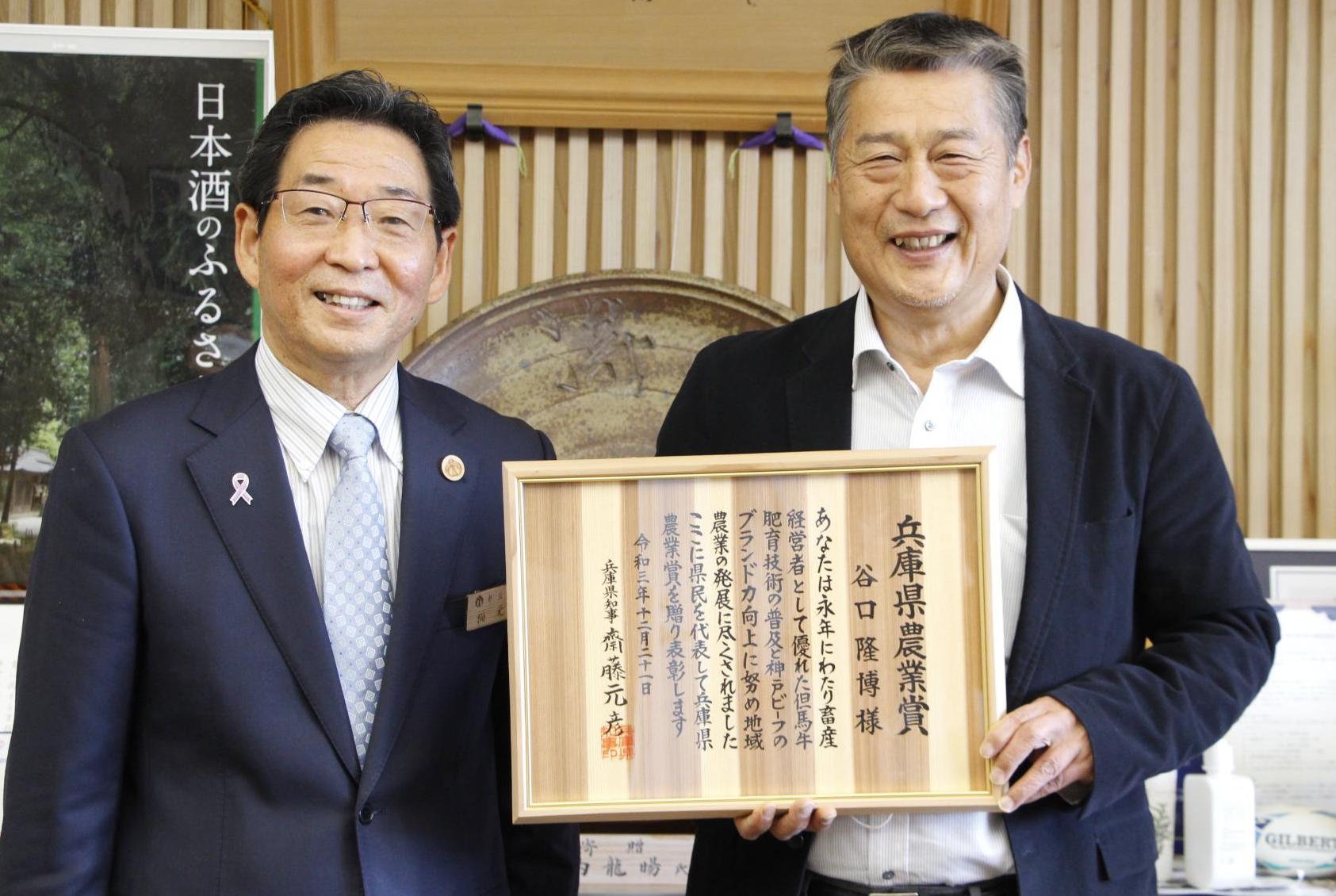 兵庫県農業賞の症状を手に笑顔を見せる山崎町の谷口隆博さんと宍粟市長が並んで微笑んでいる写真