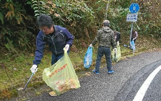 一宮町の坂の辻峠で環境美化委員らがごみ袋を持って清掃活動をしている写真