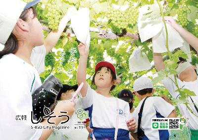 広報しそう8月号表紙 一宮北学園の児童らが山崎町のブドウ園で体験した袋かけ作業の写真