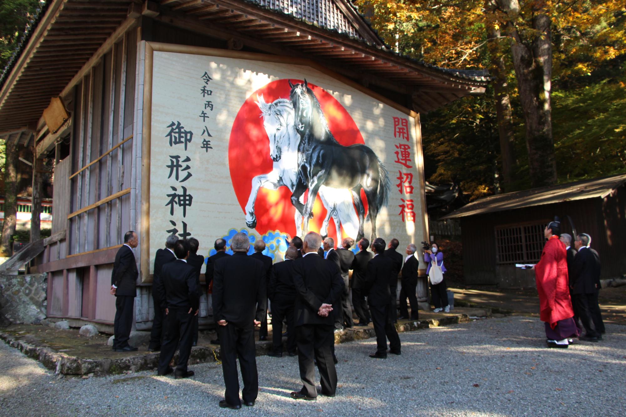 披露された巨大絵馬と見上げる参拝者