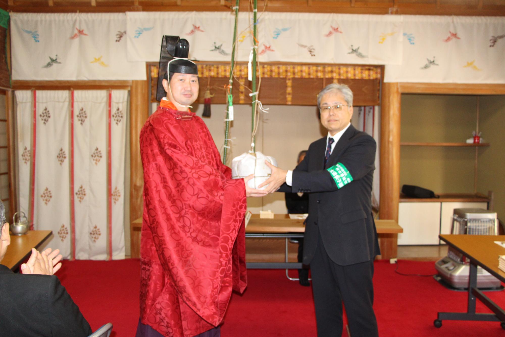 里帰り式で山田場長から進藤宮司に手渡されるショウフクジザクラの苗木