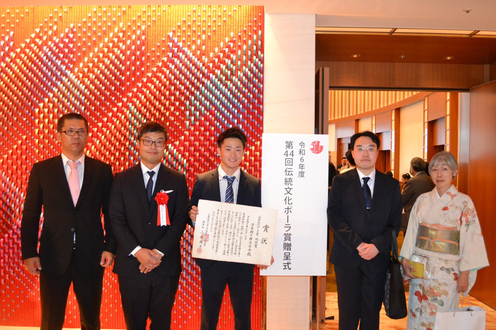 賞状を手に関係者らが会場前に撮影した記念写真