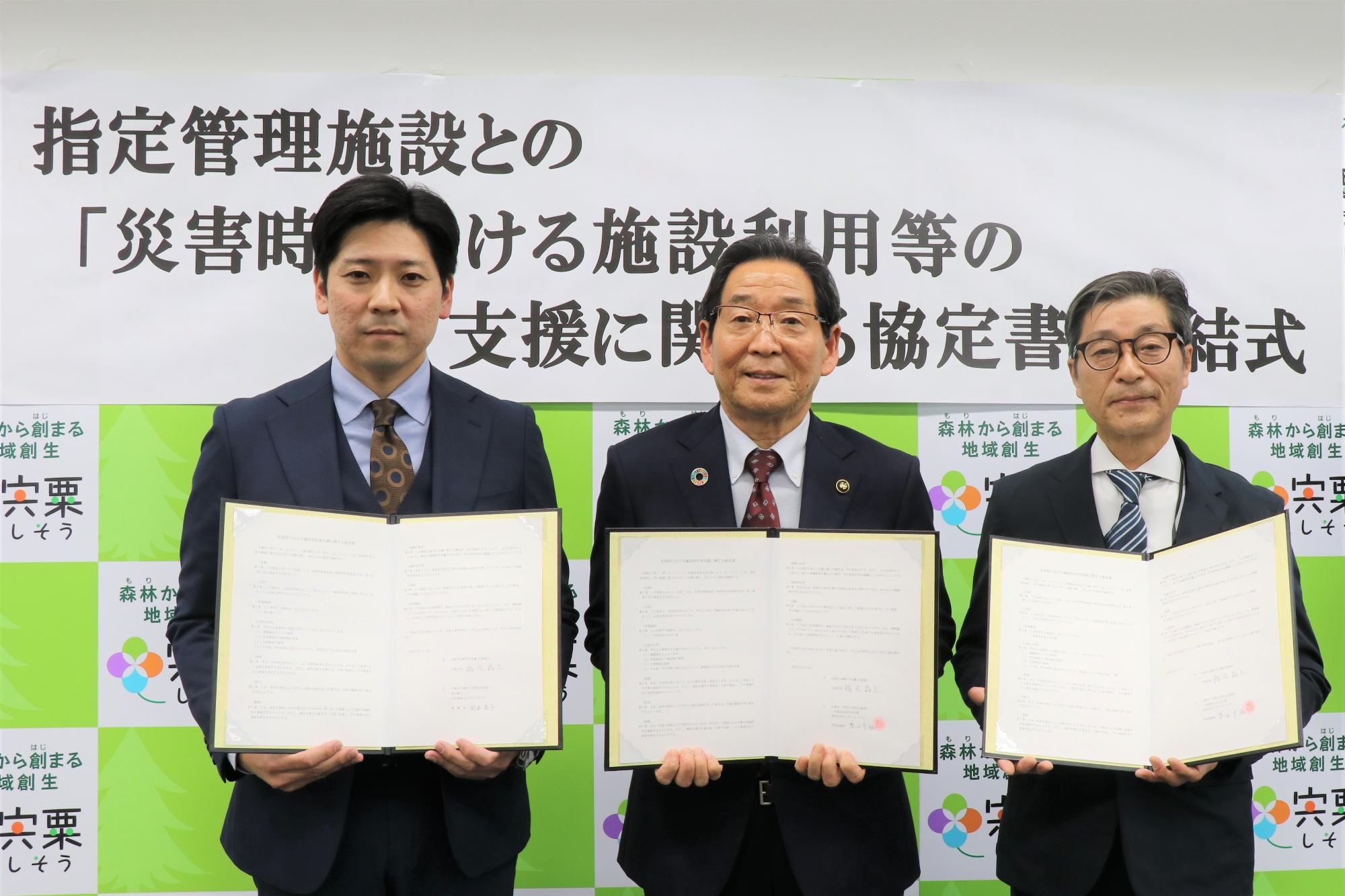 協定書を持つ、社会福祉法人はなさきむら藤川業務執行理事（左）と福元市長（中央）と株式会社ビーバーレコード中西雄樹業務執行理事