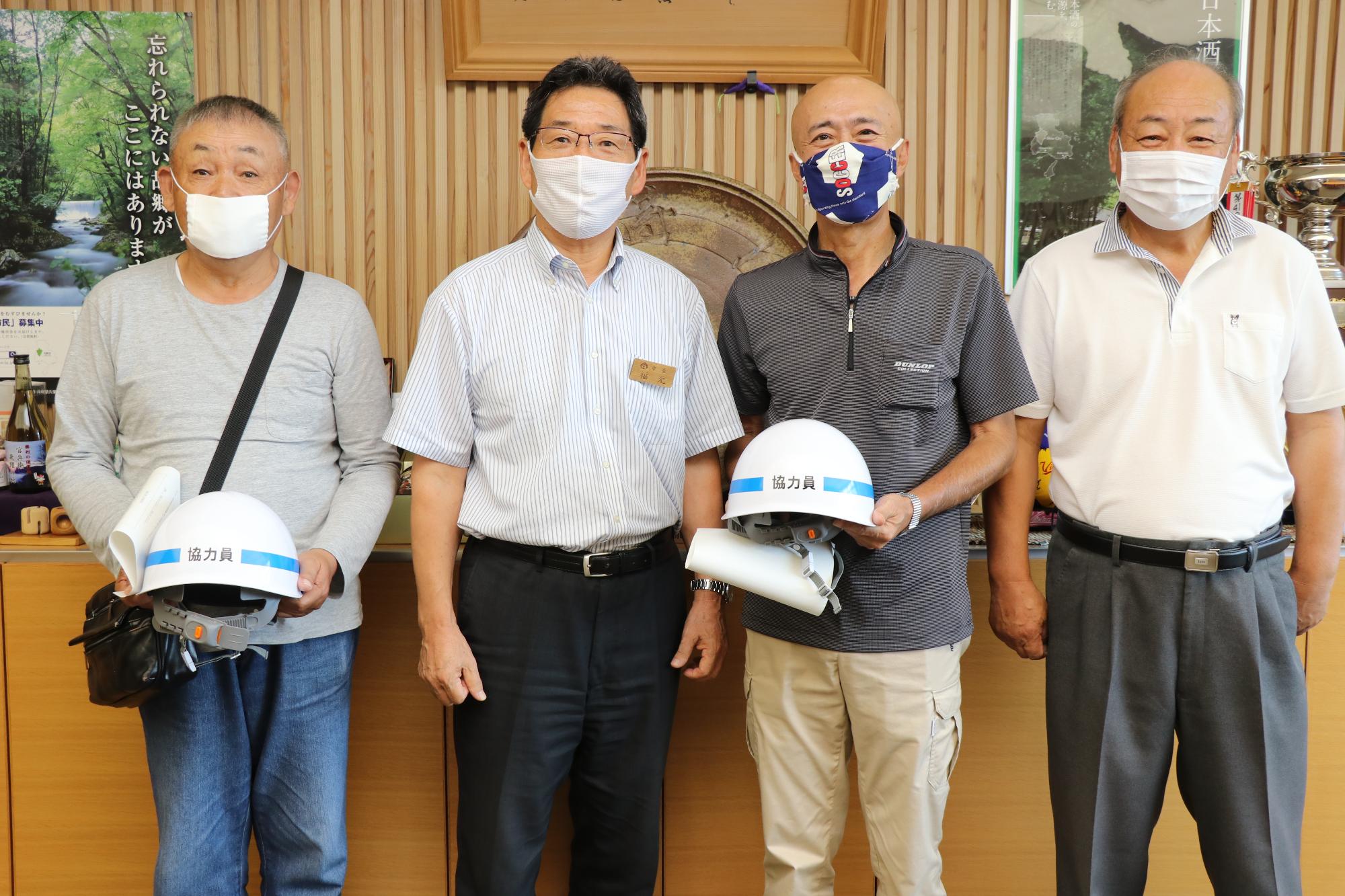 消防協力員のヘルメットを持つ岡本さんと清水さん