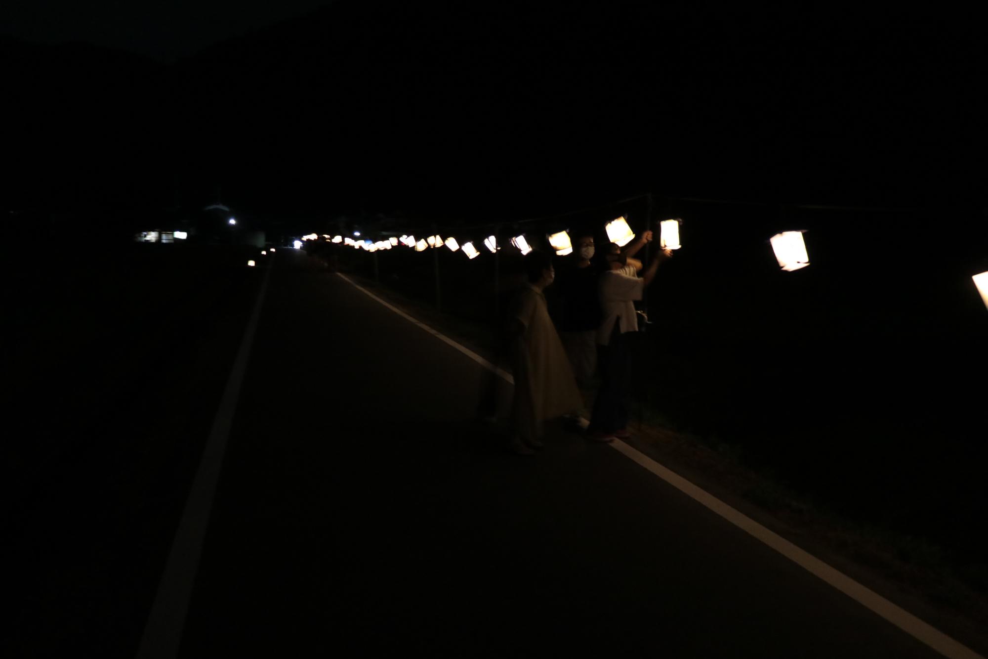 吊り下げられた提灯を見上げる住民らの写真